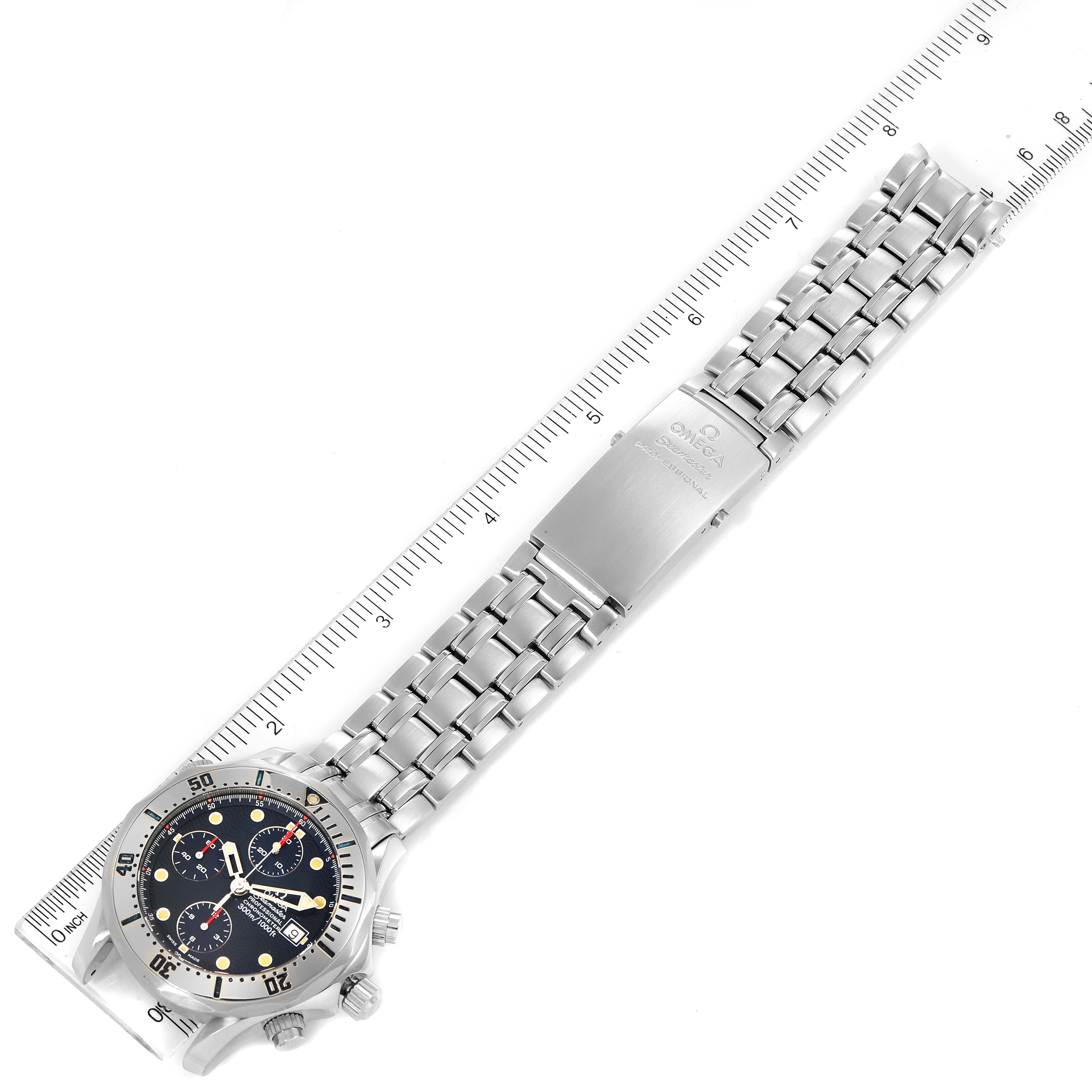 The Omega Seamaster 2598.80.00 Men
s Stainless Steel Blue Dial 2598.80.00 Men
s Stainless Steel Blue Dial watch is shown lying flat with its face, bezel, bracelet, and clasp visible, alongside a measuring ruler.