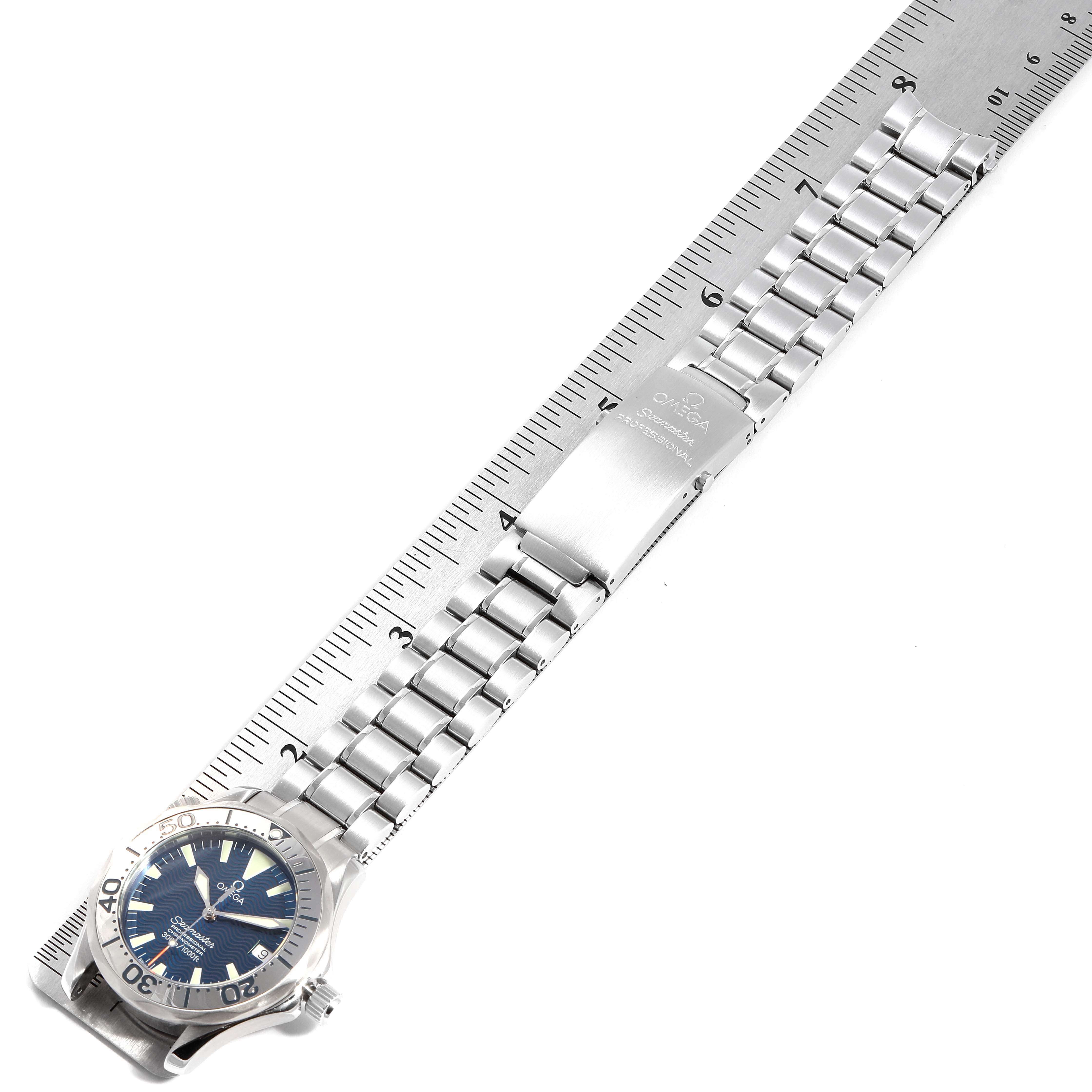 The image shows an Omega Seamaster 2553.80.00 Men
s Stainless Steel Blue Dial 2553.80.00 Men
s Stainless Steel Blue Dial watch laid on a ruler, displaying the bracelet, clasp, case, and part of the dial.