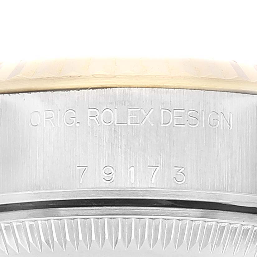 Close-up of the side of a Rolex Datejust 79173 Women's Steel and Gold (two tone) Grey Dial 79173 Women's Steel and Gold (two tone) Grey Dial model, showing engraved text and partial view of the bezel and case.