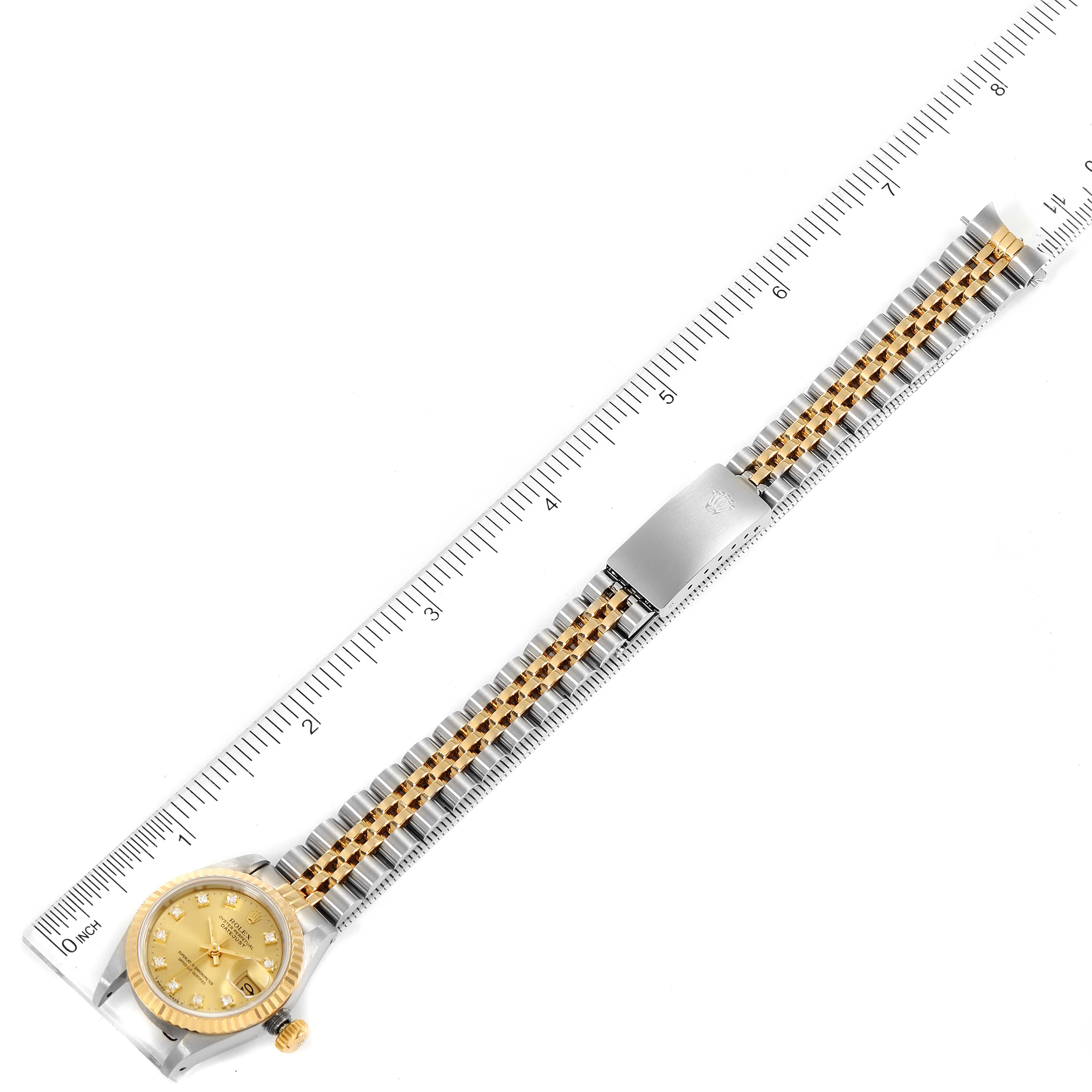 The Rolex Datejust 69173 Women
s Steel and Gold (two tone) Champagne Dial 69173 Women
s Steel and Gold (two tone) Champagne Dial watch is shown from a top-down angle, displaying its dial, bezel, and full bracelet next to a ruler.