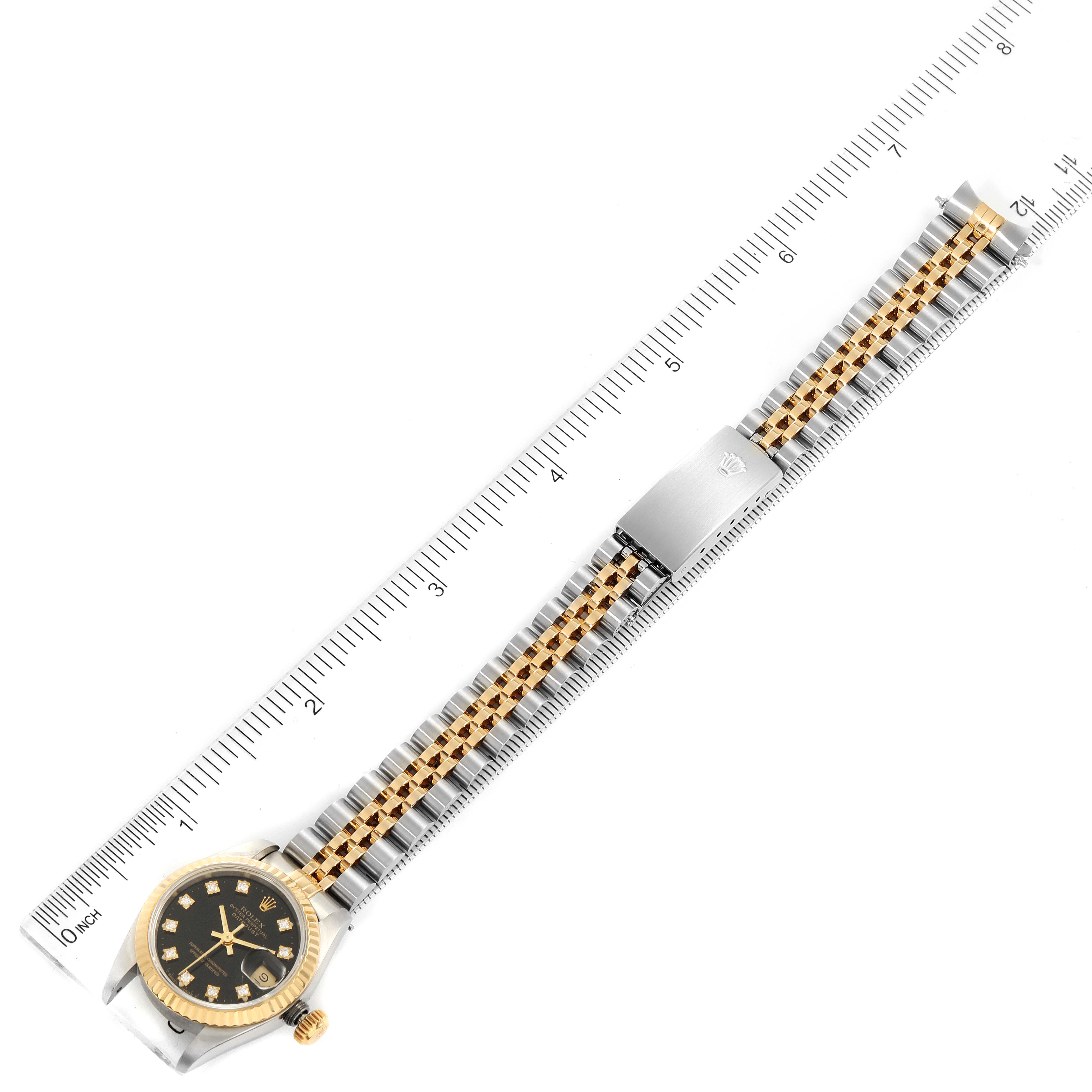 This image shows a full view of the Rolex Datejust 69173 Women's Steel and Gold (two tone) Black Dial 69173 Women's Steel and Gold (two tone) Black Dial watch, including its face, bezel, and bracelet, positioned next to a ruler for scale.