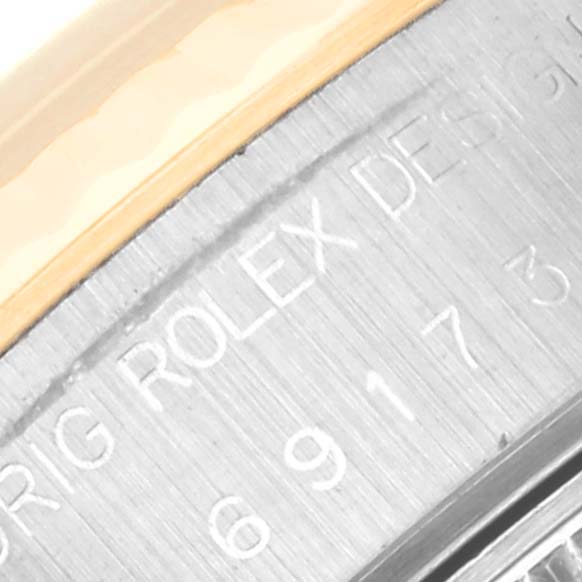 Close-up of the engraved bezel edge of a Rolex Datejust 69173 Women's Steel and Gold (two tone) Champagne Dial 69173 Women's Steel and Gold (two tone) Champagne Dial watch, displaying part of the serial number and "ORIG ROLEX DESIGN".