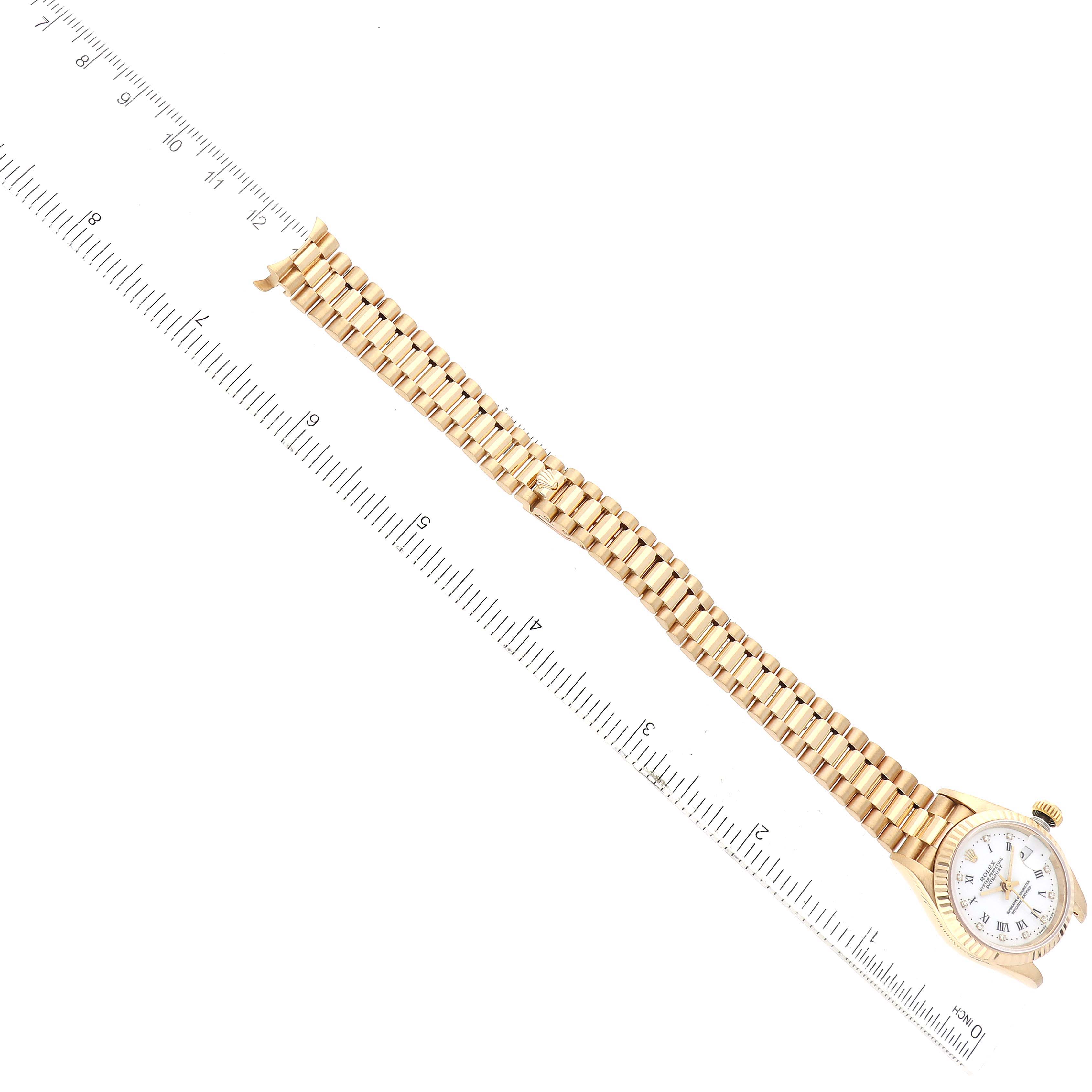 The image shows a Rolex President 69178 Women's Yellow Gold White Dial 69178 Women's Yellow Gold White Dial watch laid flat next to a ruler, displaying its band and face from a top-down angle.
