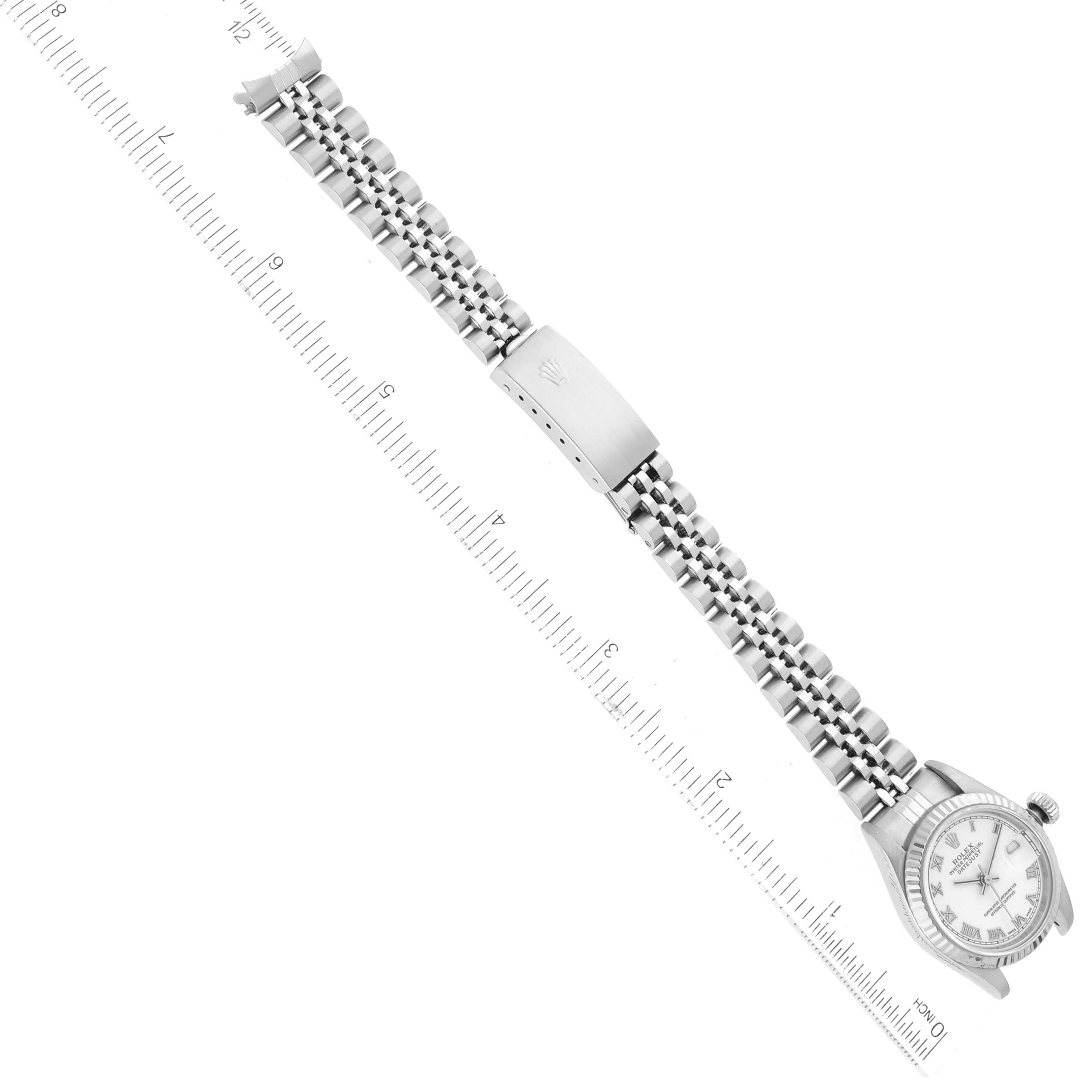 This image shows the Rolex Datejust 79174 Women's Stainless Steel White Dial 79174 Women's Stainless Steel White Dial watch laid flat with a ruler for measurement, highlighting the dial, bracelet, and clasp.