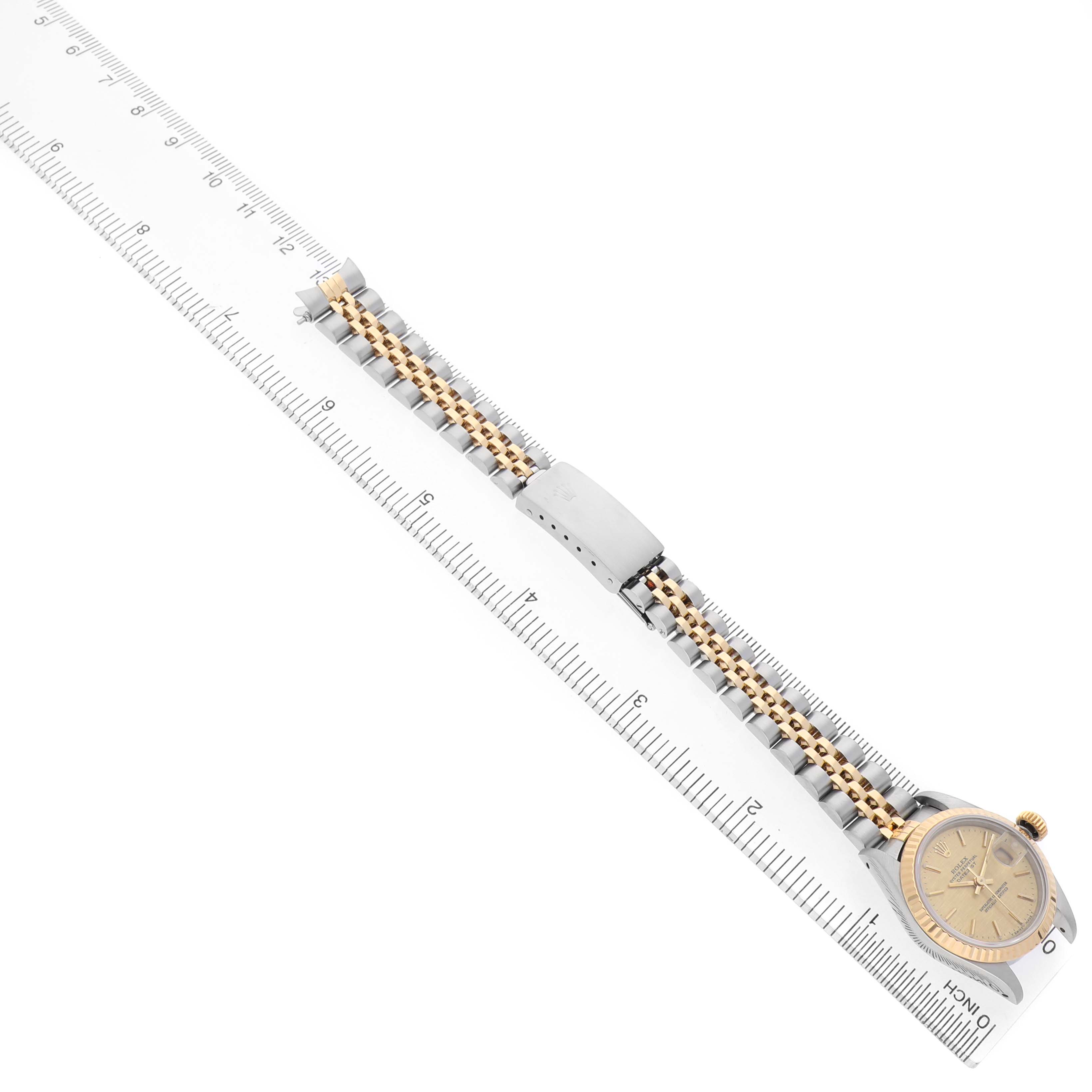 The Rolex Datejust 69173 Women's Steel and Gold (two tone) Champagne Dial watch is shown from a top-down angle, displaying the face, bezel, and full bracelet with a ruler beside it.