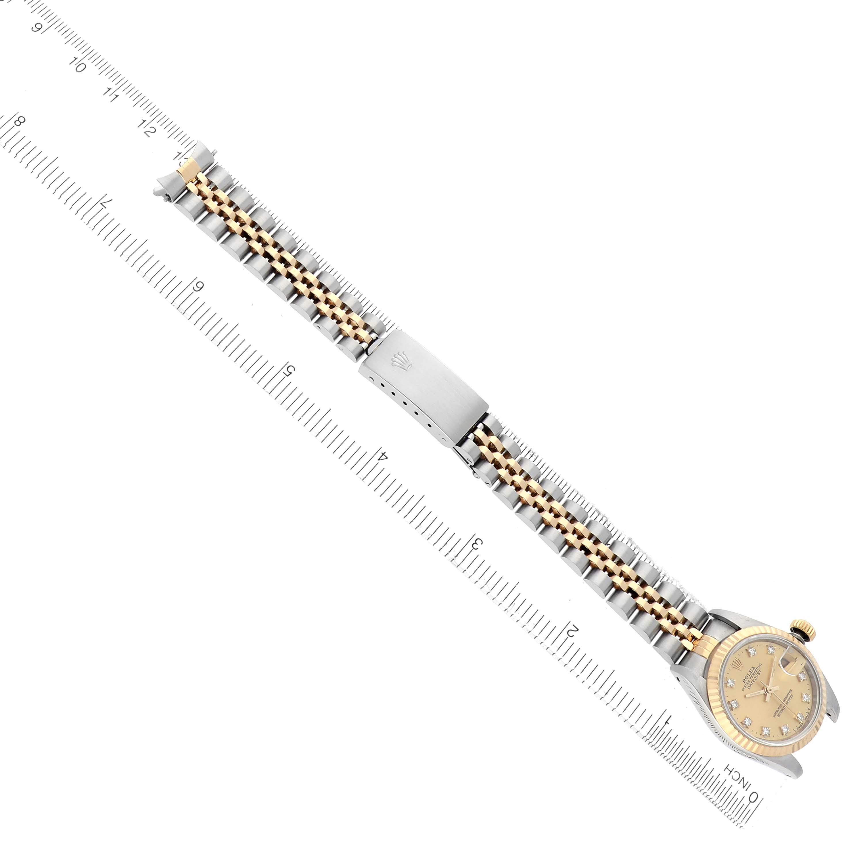 The Rolex Datejust 69173 Women's Steel and Gold (two tone) Champagne Dial 69173 Women's Steel and Gold (two tone) Champagne Dial watch is shown at a diagonal angle, displaying the full bracelet and face, with a measuring ruler beneath.