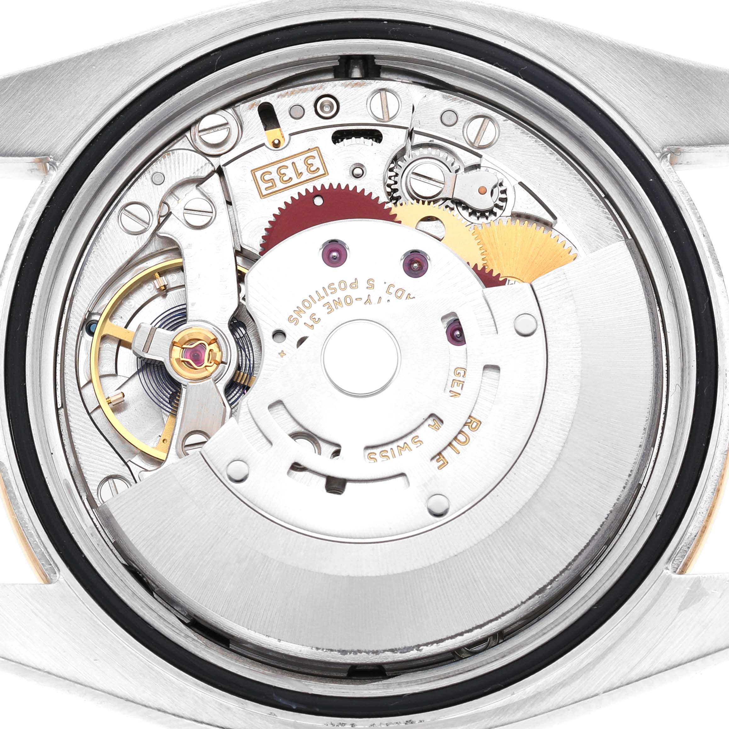 The image shows the movement of a Rolex Datejust 116243 Men's Steel and Gold (two tone) Black Dial watch, viewed from the back, highlighting the intricate gears and mechanisms.