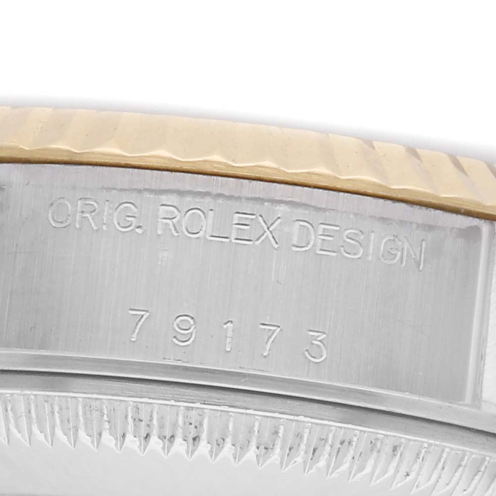 The image shows a close-up of the side of a Rolex Datejust 79173 Women's Steel and Gold (two tone) White Dial 79173 Women's Steel and Gold (two tone) White Dial watch, featuring the case with engraved design details and serial number.