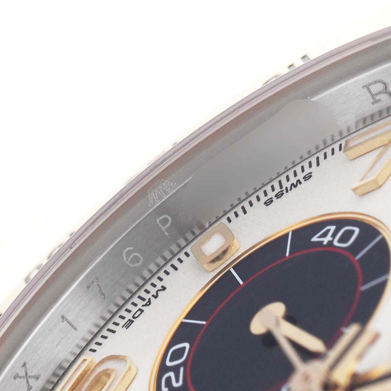 The image shows a close-up of the Rolex Daytona 116523 Men's Steel and Gold (two tone) Silver Dial dial and bezel, focusing on the markers and detailing between 5 and 10.