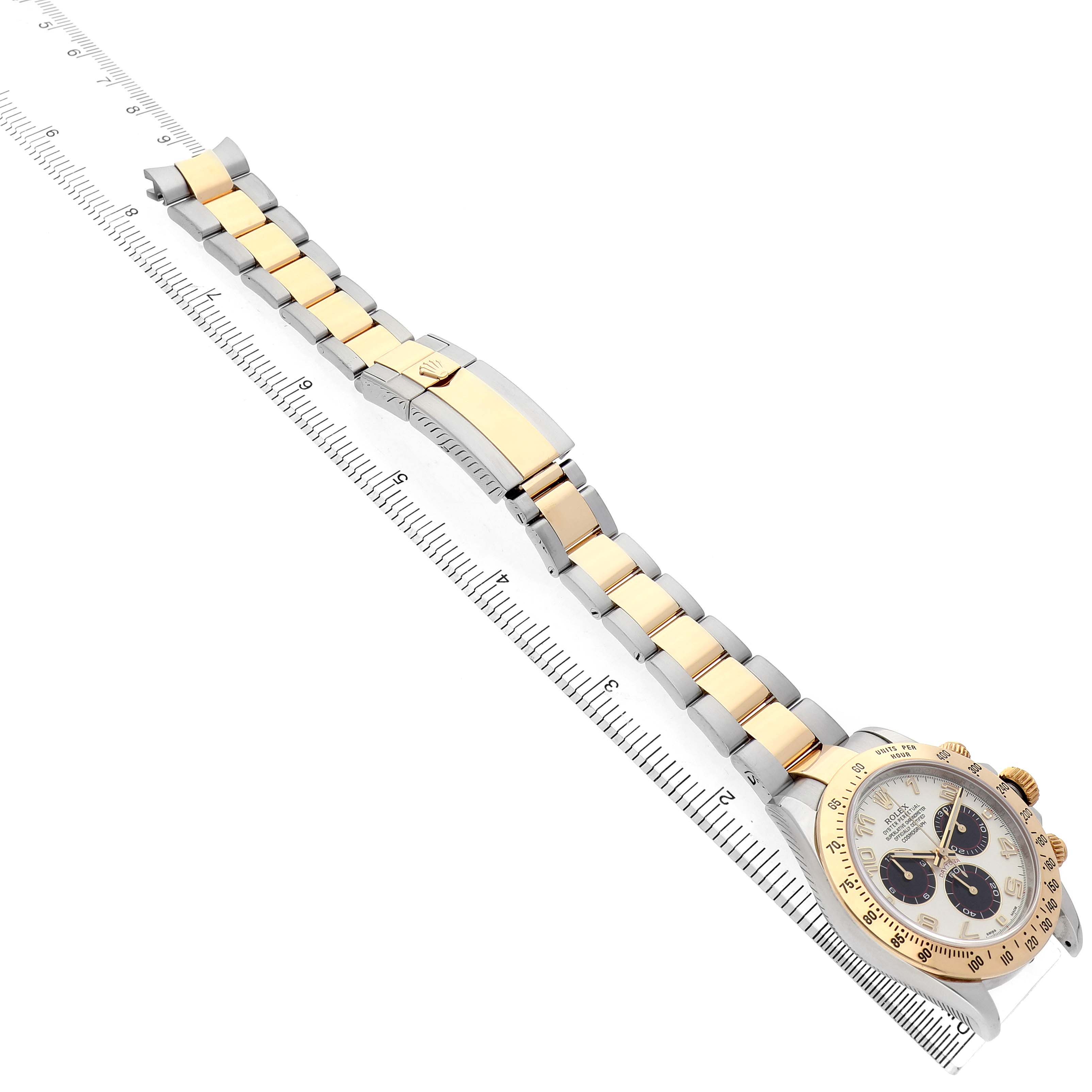 The Rolex Daytona 116523 Men's Steel and Gold (two tone) Silver Dial is shown from a top-down angle with its full bracelet, gold accents, and face visible alongside a ruler.