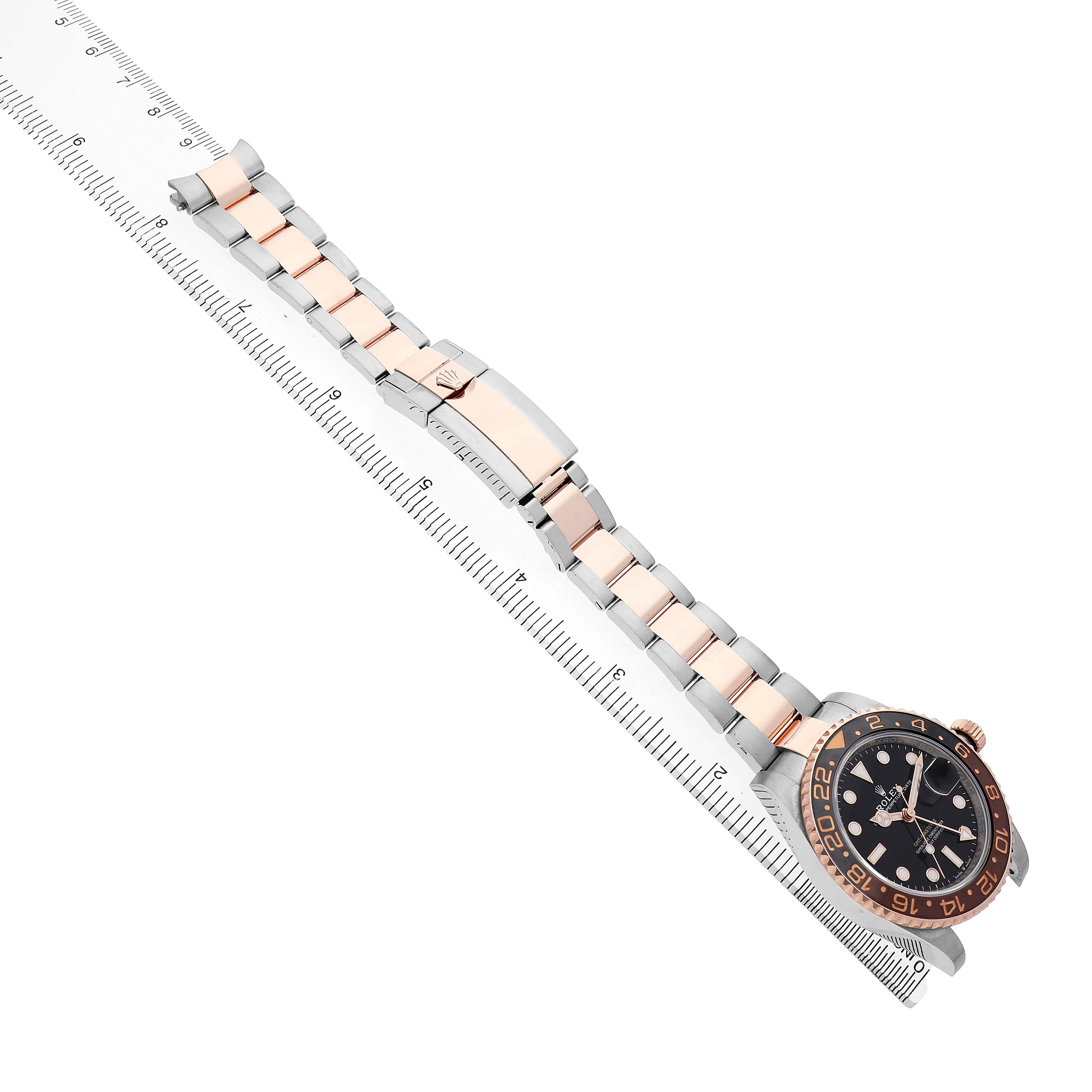 The Rolex GMT-Master 126711CHNR Men's Steel and Gold (two tone) Black Dial watch is shown from above, featuring the full bracelet and case with a ruler for scale.