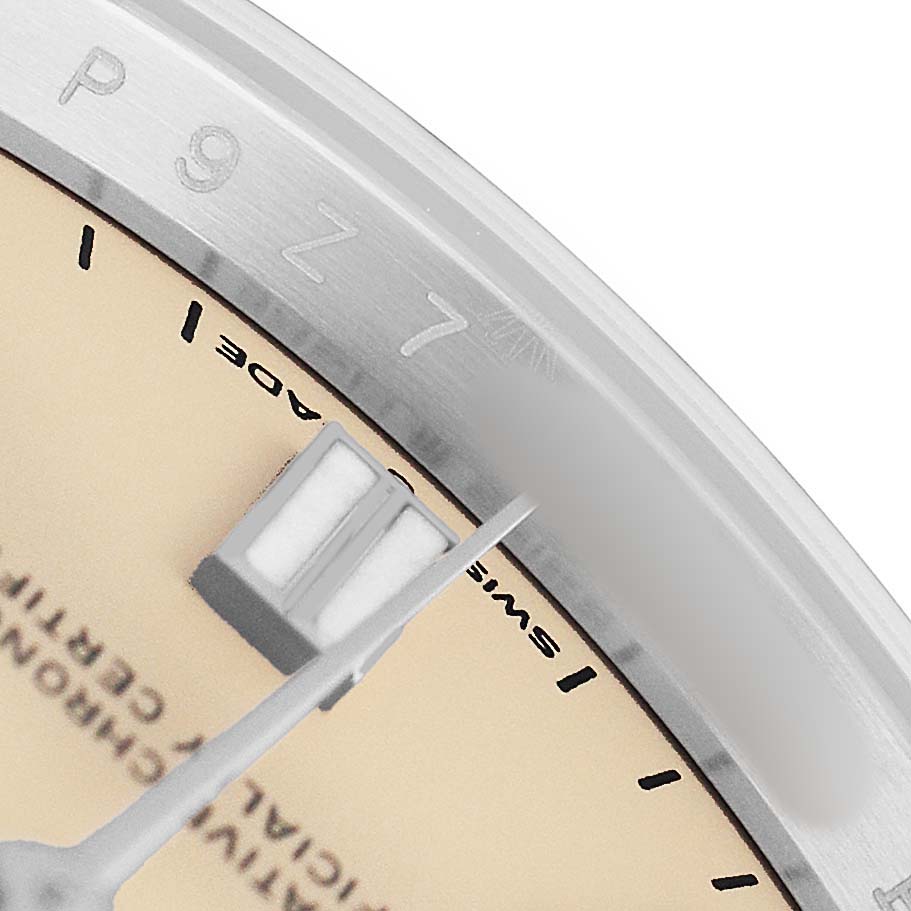 The image shows a close-up of the Rolex Oyster Perpetual M126000-0001 Men's Stainless Steel Beige Dial watch's dial, focusing on the edge with part of an index marker and the second hand.