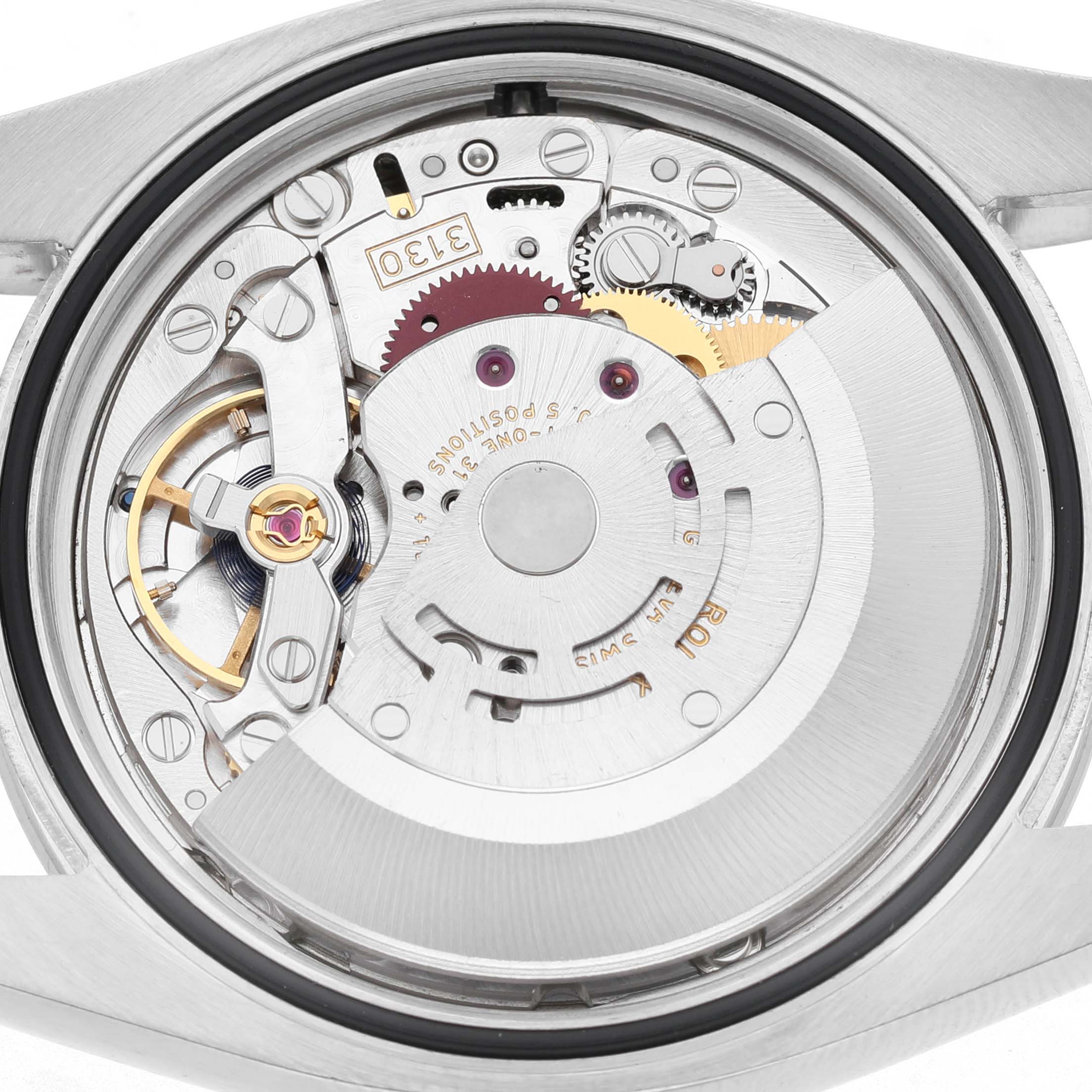 The image shows the movement of a Rolex Oyster Perpetual 116000 Men's Stainless Steel Silver Dial watch from a rear angle, displaying intricate gears and mechanisms.