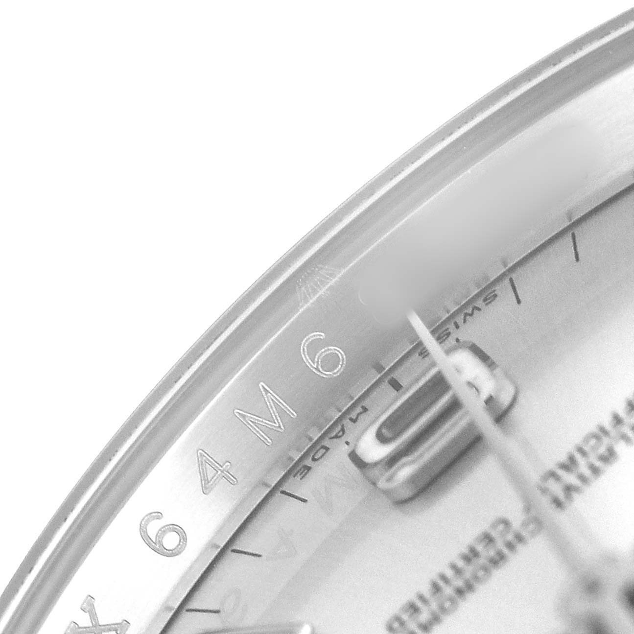 The image shows a close-up of the Rolex Oyster Perpetual 116000 Men's Stainless Steel Silver Dial watch face, highlighting part of the dial and a hand.