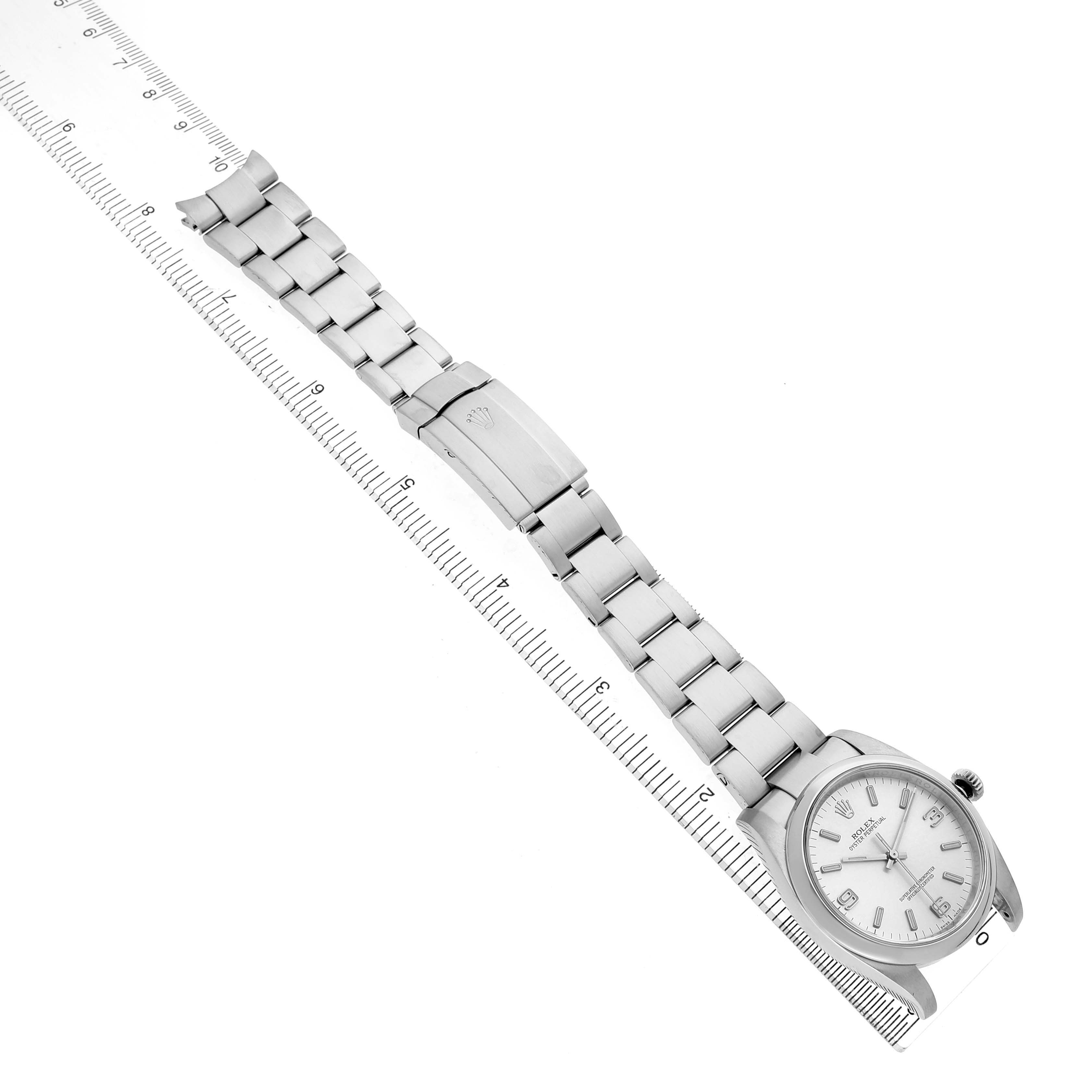 The Rolex Oyster Perpetual 116000 Men's Stainless Steel Silver Dial watch is shown from an overhead angle, displaying the full bracelet and clasp.