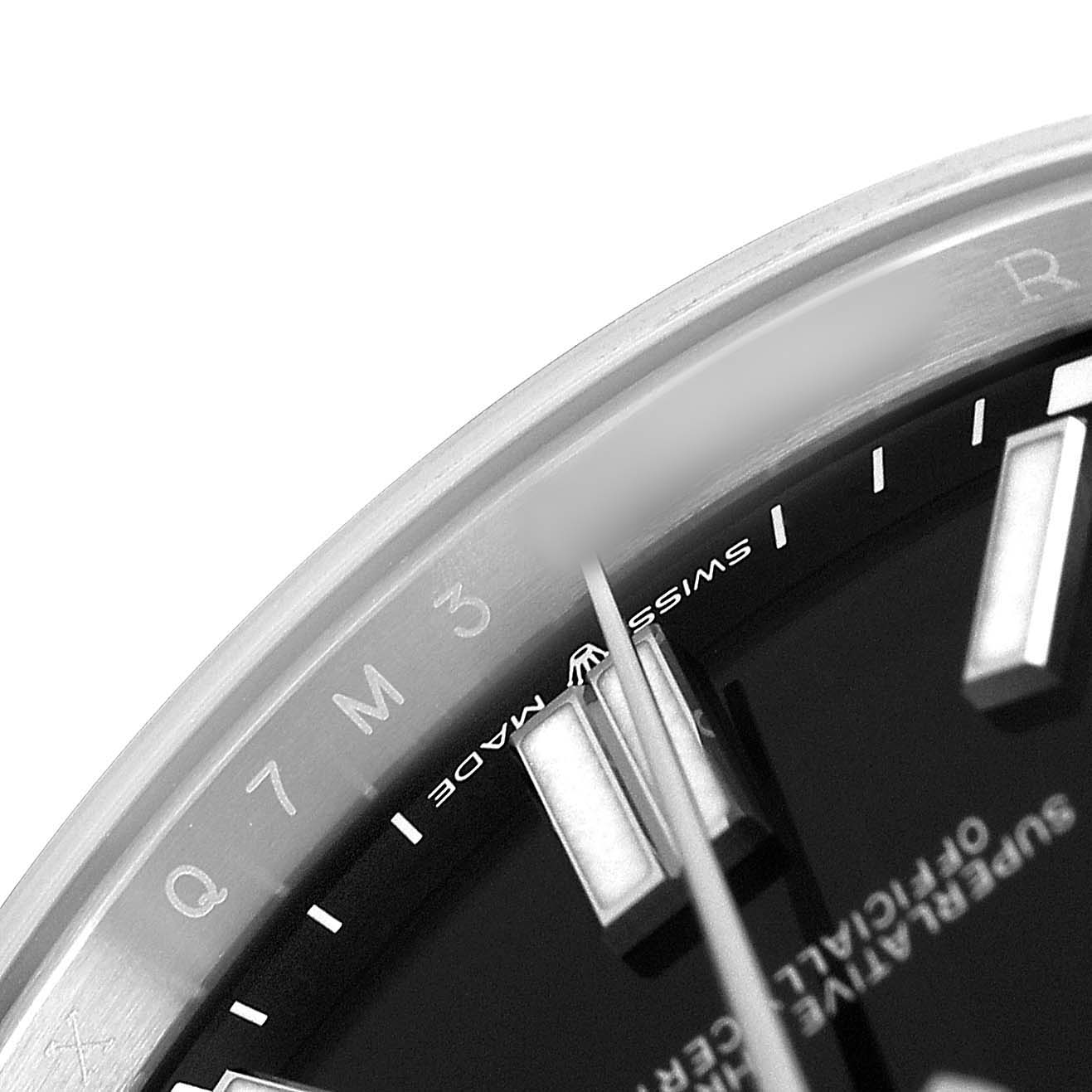 The image shows a close-up angle of the Rolex Oyster Perpetual M124300-0002 Men's Stainless Steel Black Dial’s dial and bezel, highlighting the hour markers and part of the hands.