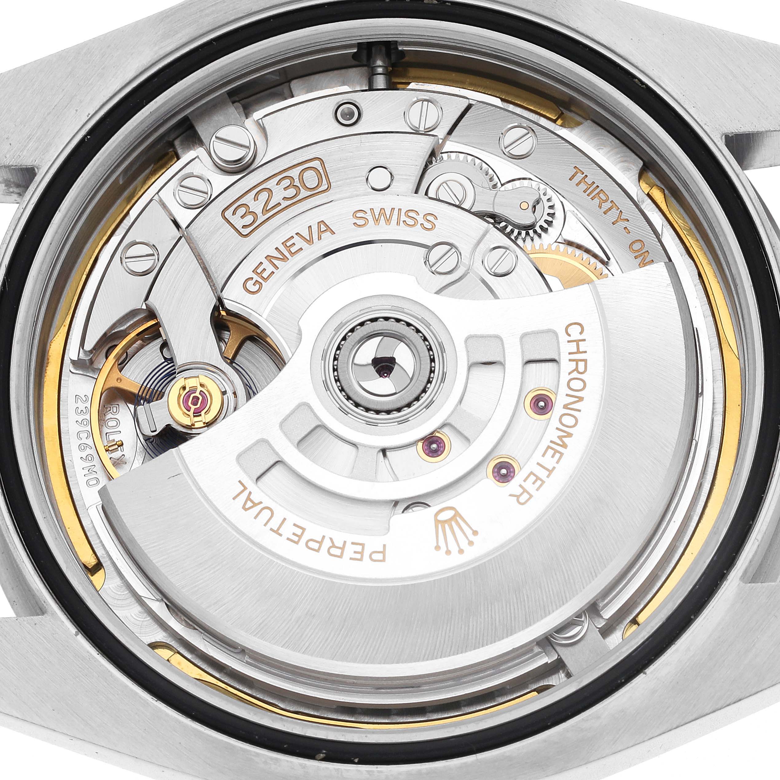 The image shows the movement of a Rolex Air-King 126900 Men's Stainless Steel Black Dial 126900 Men's Stainless Steel Black Dial watch from the back, highlighting gears and inscriptions.