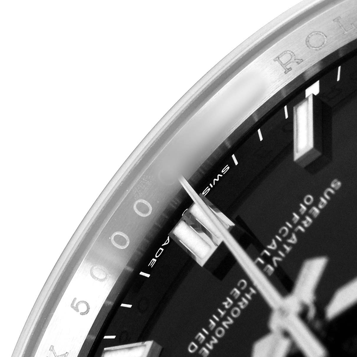 The image shows a close-up of the dial, markers, and hands of a Rolex Oyster Perpetual 126000 Men's Stainless Steel Black Dial watch, viewed from an angle near the bezel.