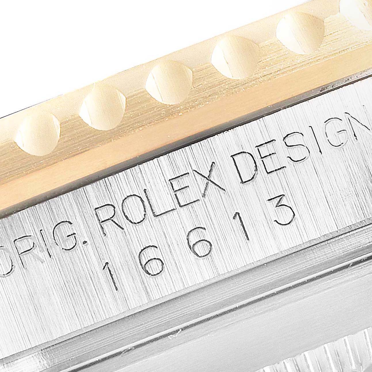 This close-up image shows the engraved model number and "Rolex Design" inscription on the side of a Rolex Submariner 16613 Men
s Steel and Gold (two tone) Blue Dial 16613 Men
s Steel and Gold (two tone) Blue Dial watch case.