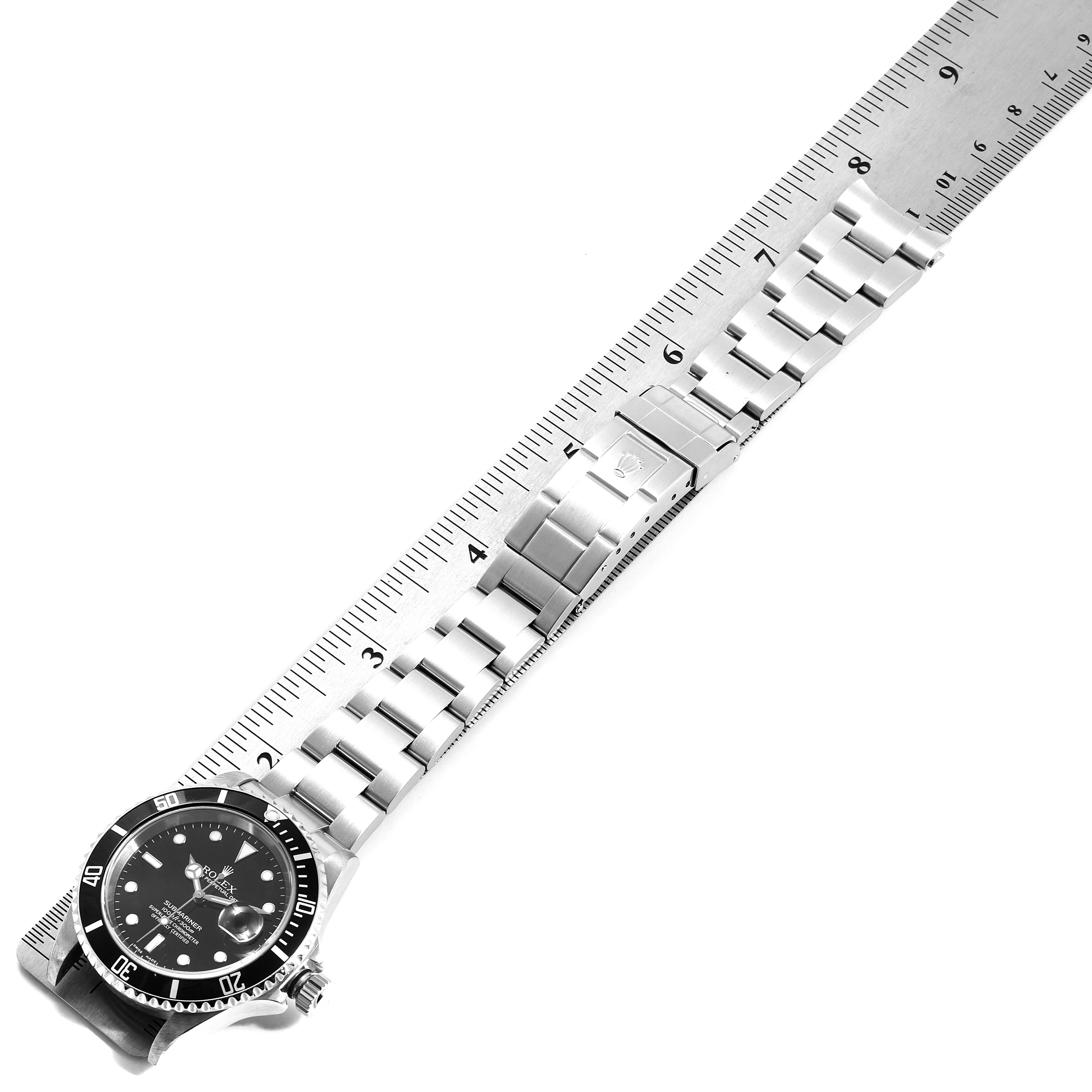 This image shows the full length of the Rolex Submariner 16610 Men
s Stainless Steel Black Dial 16610 Men
s Stainless Steel Black Dial watch, including its face, bezel, and metal bracelet, positioned beside a ruler.