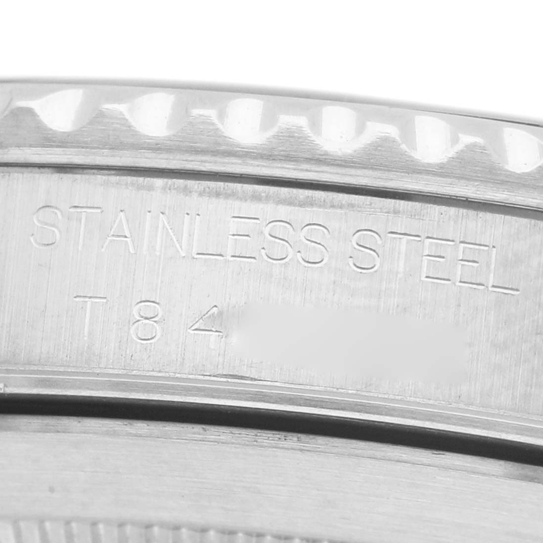 The image shows a close-up of the side engraving on a Rolex Submariner 14060M Men's Stainless Steel Black Dial, highlighting "Stainless Steel" and part of its serial number.