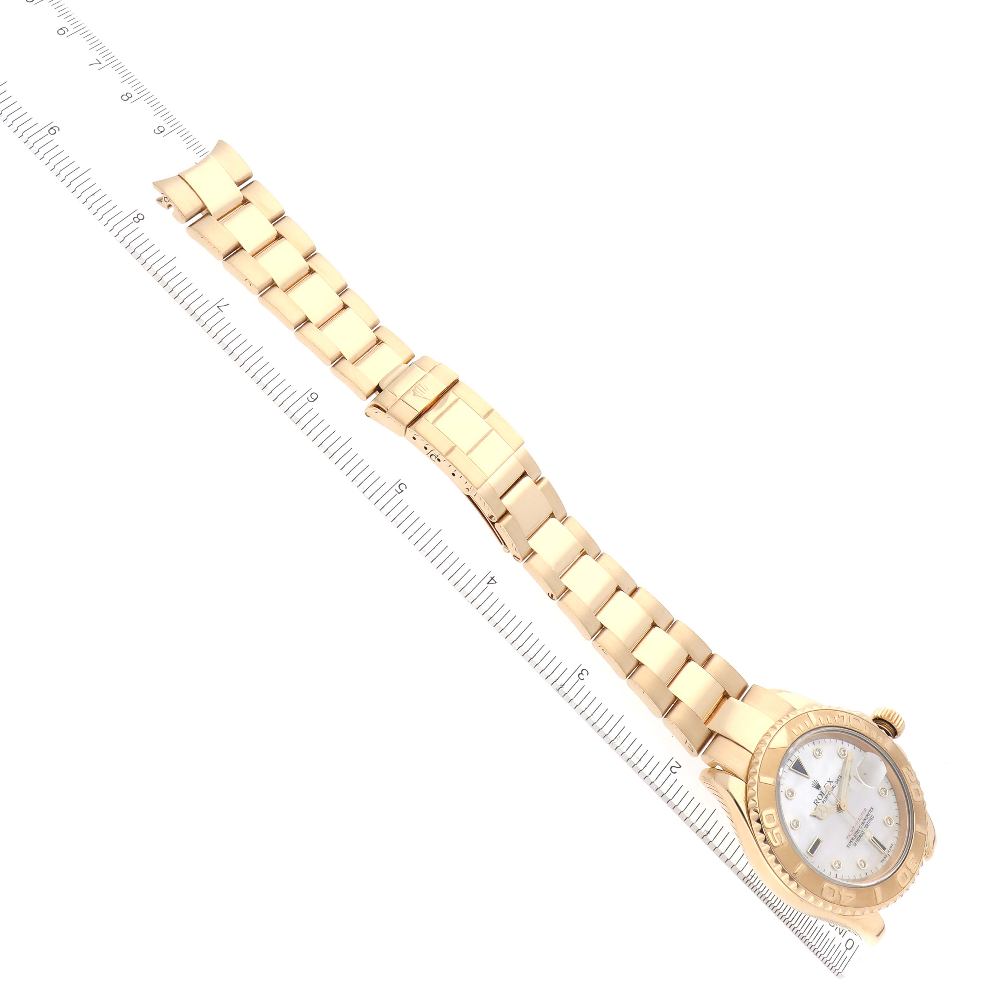 The Rolex Yacht-Master 16628 Men
s Yellow Gold Mother of Pearl Dial 16628 Men
s Yellow Gold Mother of Pearl Dial watch is displayed at a diagonal angle, showing its full gold bracelet and face next to a ruler for scale.