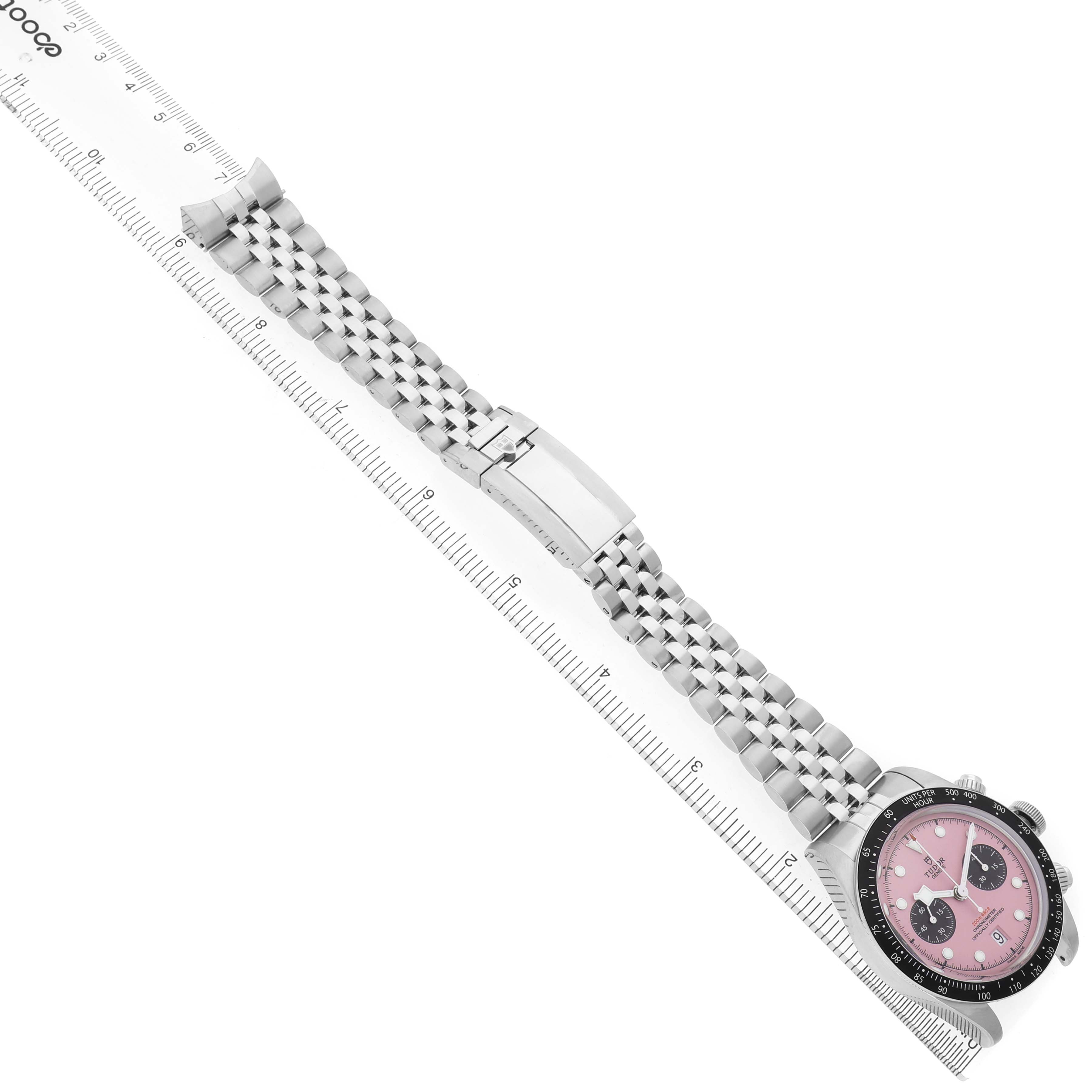 The image shows a Tudor Heritage Chrono M79360N-0019 Men's Stainless Steel Pink Dial watch with a pink dial and stainless steel bracelet laid next to a ruler.