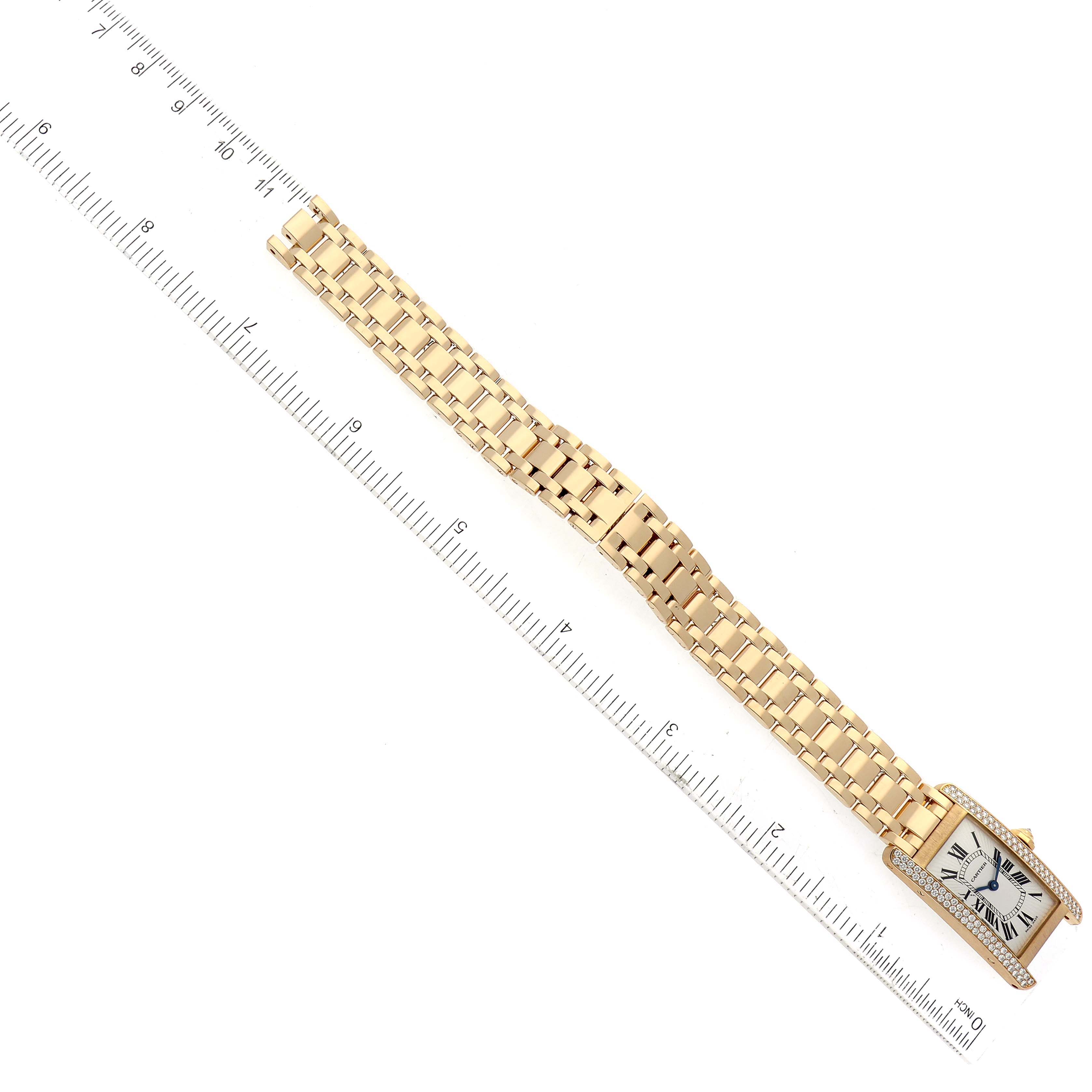 The Cartier Tank Americaine WB7012K2 Women's Yellow Gold Silver Dial WB7012K2 Women's Yellow Gold Silver Dial watch is shown flat, displaying its gold bracelet, rectangular face, and a ruler for scale.