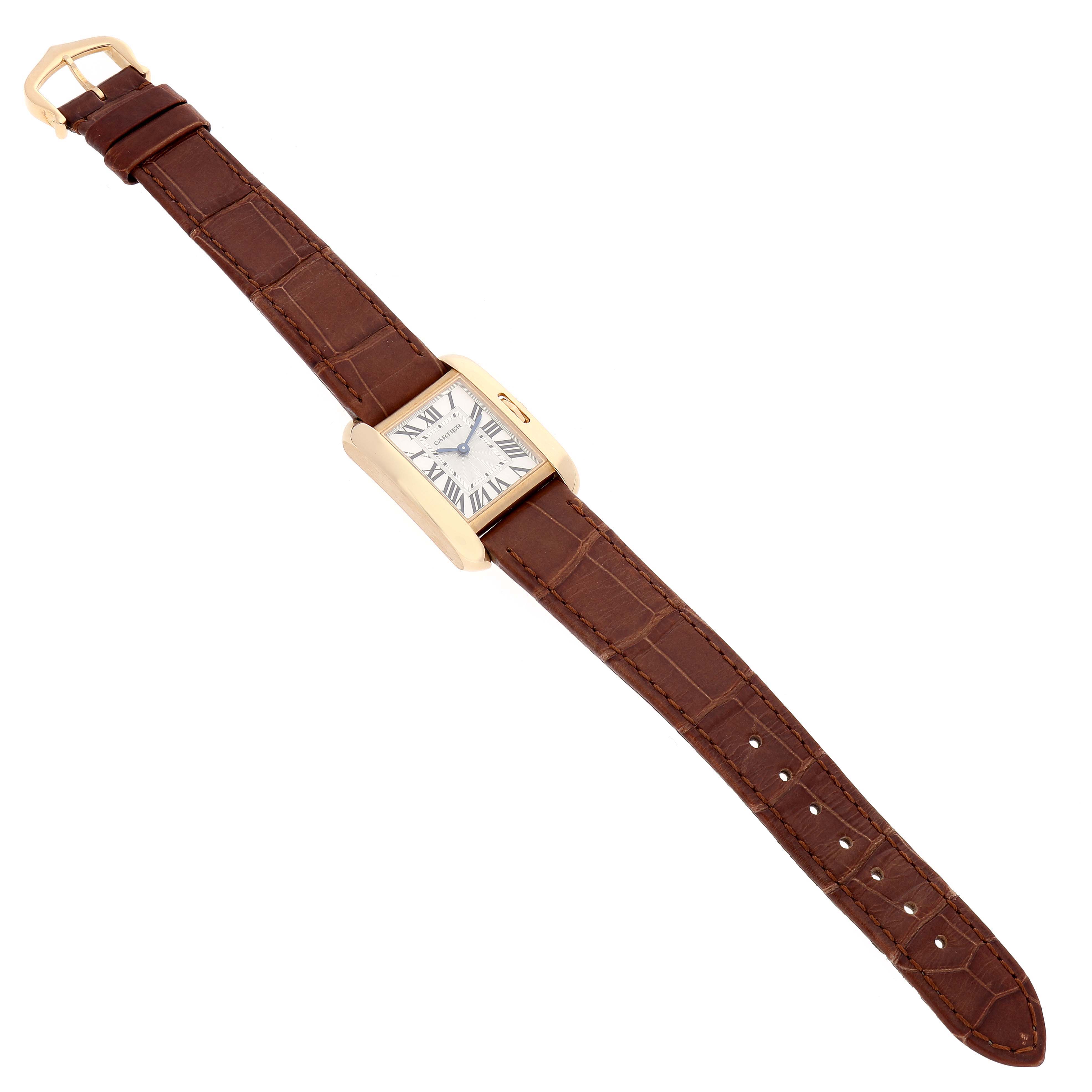 The image shows a top-down view of a Cartier Tank Anglaise W5310028 Women
s Yellow Gold Silver Dial W5310028 Women
s Yellow Gold Silver Dial watch with a brown leather strap and a rectangular gold case.