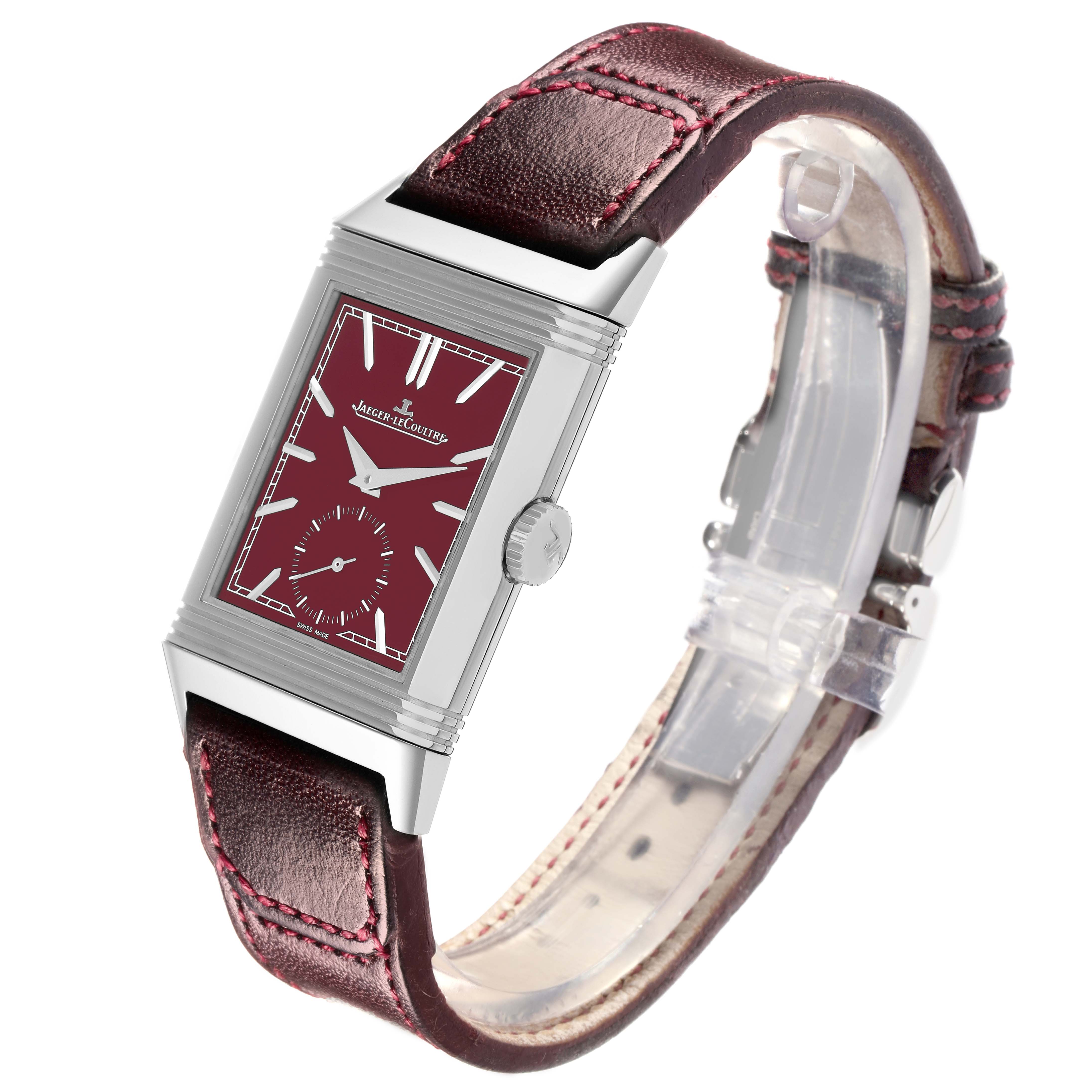The Jaeger-LeCoultre Reverso watch is shown at an angle highlighting the burgundy dial, silver case, crown, and leather strap.