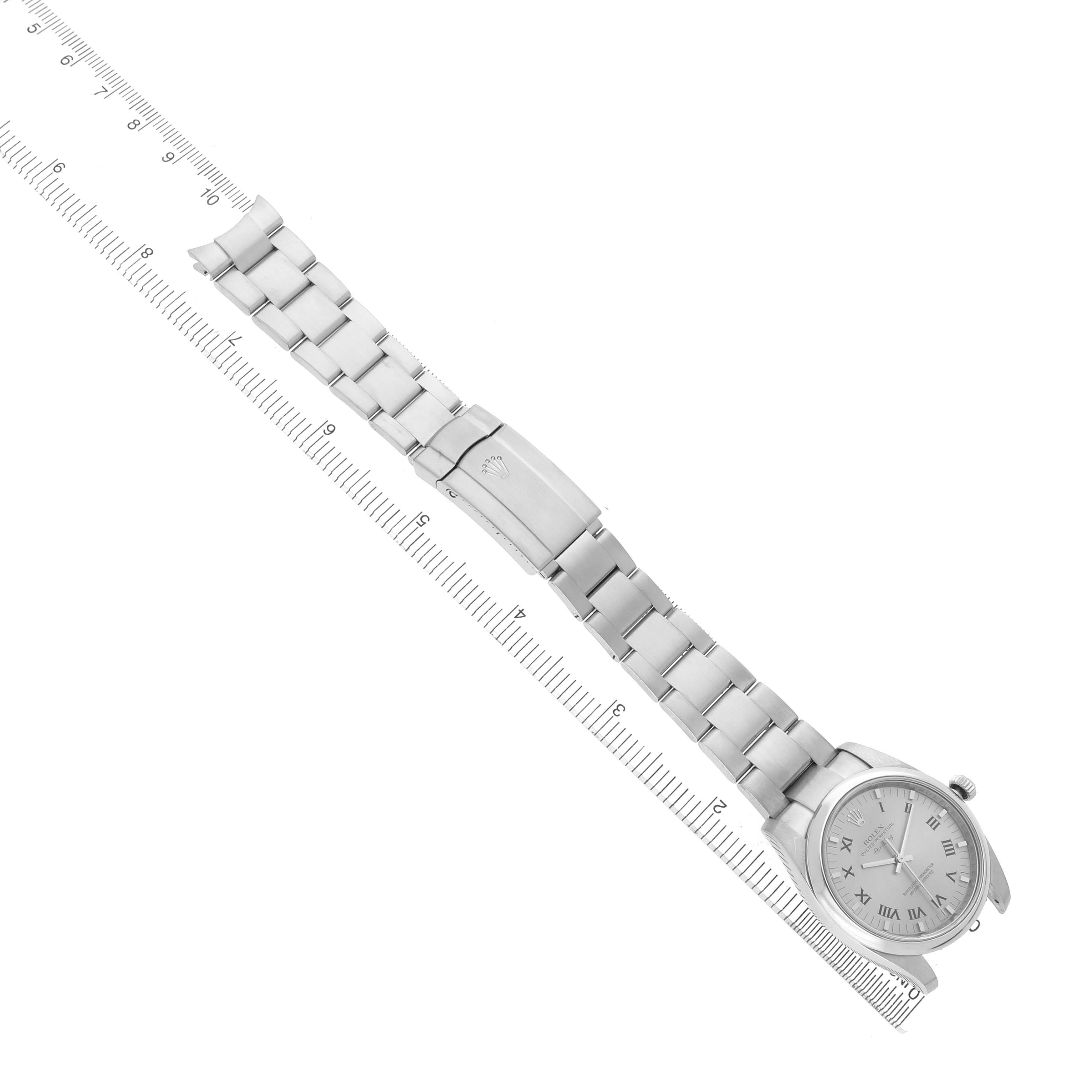 The Rolex Air-King 114200 Men's Stainless Steel Silver Dial watch is shown from a top-down angle, displaying the entire bracelet, clasp, and face aligned with a ruler.