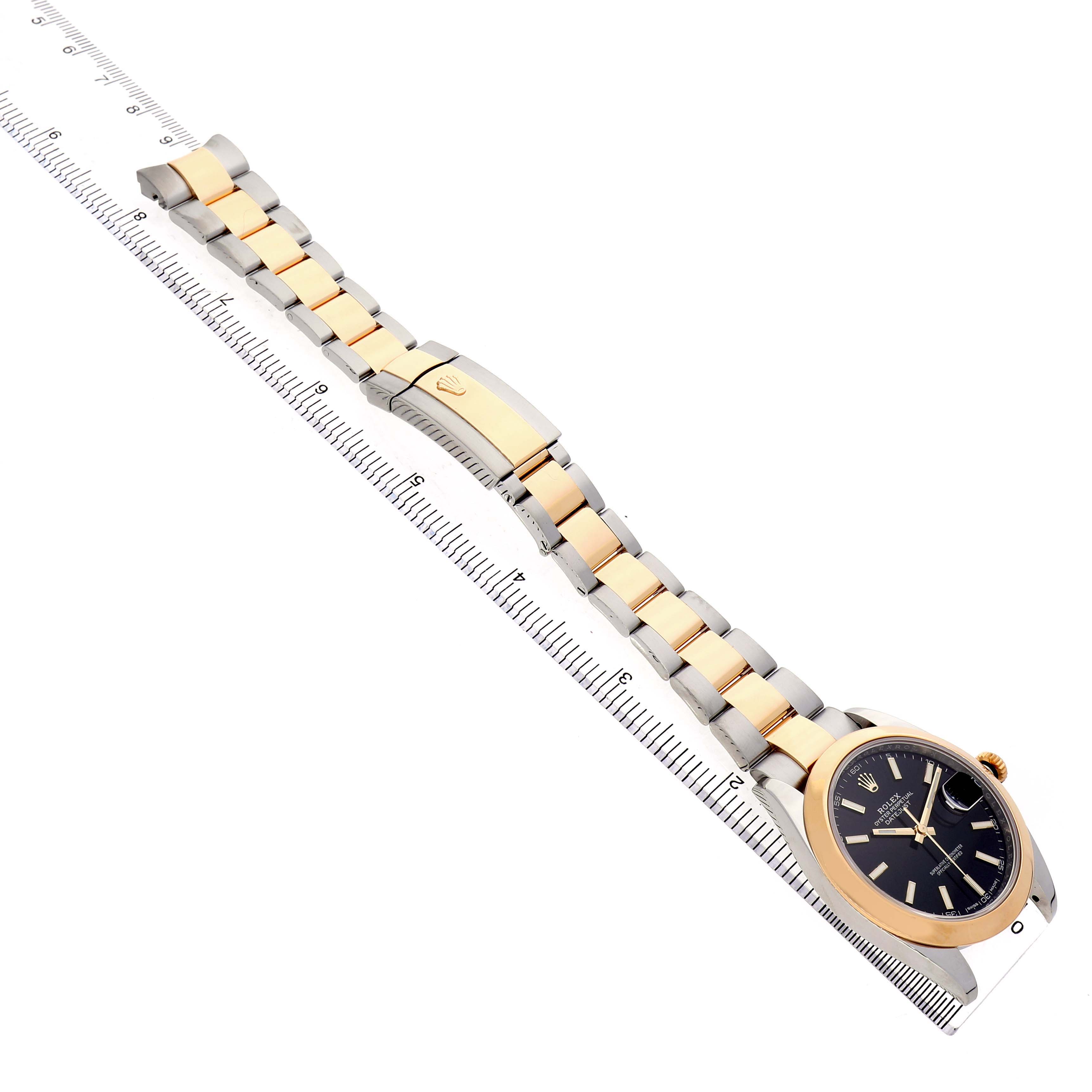 The Rolex Datejust 41 126303 Men's Steel and Gold (two tone) Black Dial is displayed diagonally, showing the full bracelet and face at an elevated angle alongside a ruler.