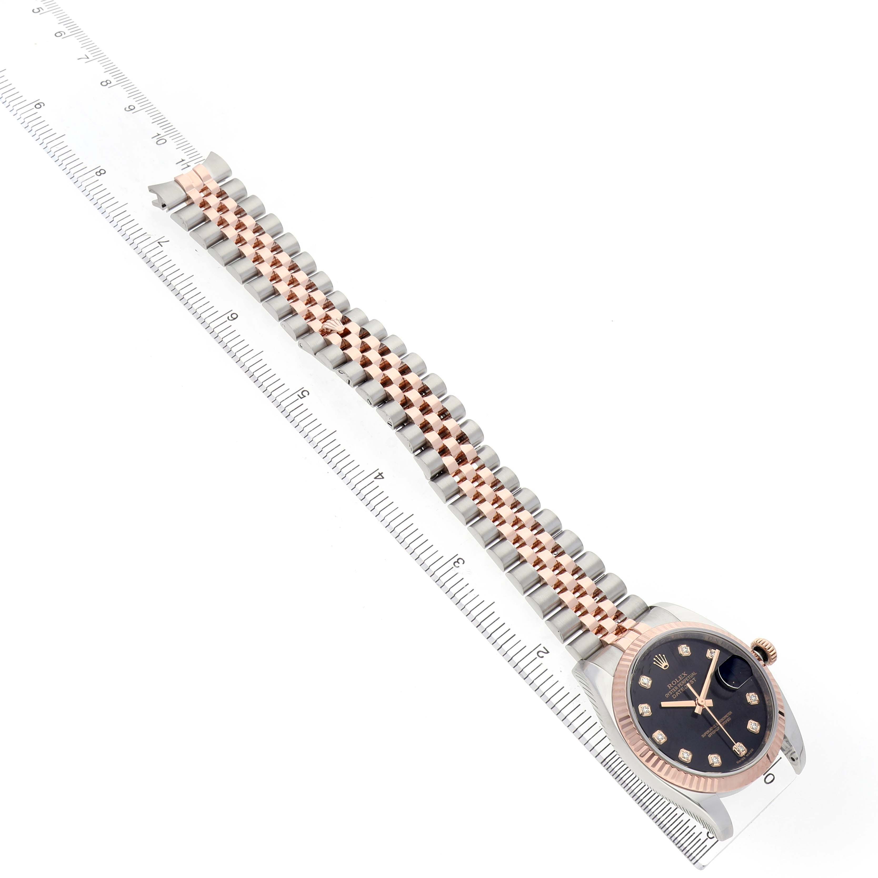 The Rolex Datejust 116231 Men's Steel and Gold (two tone) Black Dial watch is shown from a top view, highlighting the face, bezel, crown, and the Jubilee bracelet alongside a ruler.


