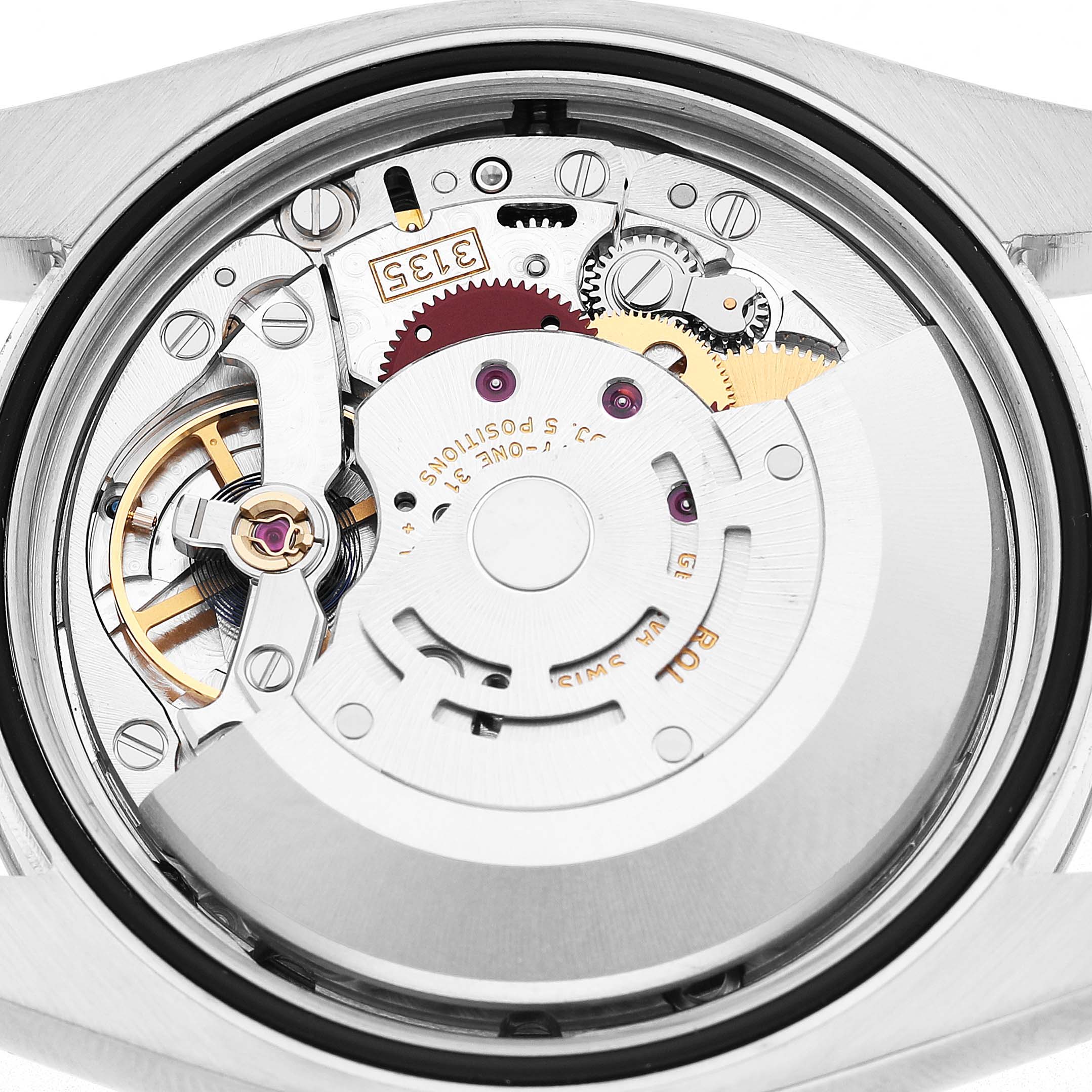 The image shows the movement of a Rolex Datejust 116234 Men's Stainless Steel White Dial watch from a rear angle, highlighting gears and mechanical components.