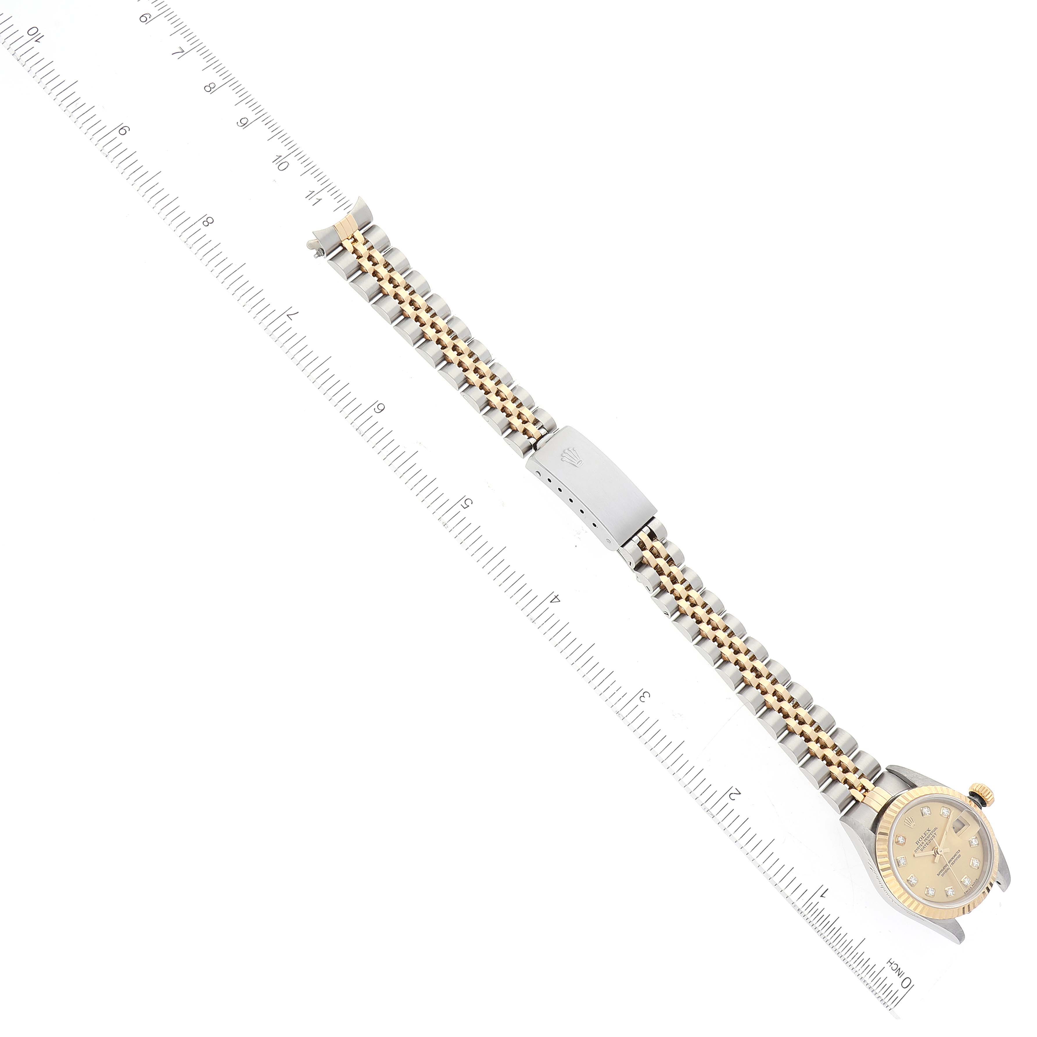The image shows the Rolex Datejust 79173 Women's Steel and Gold (two tone) Champagne Dial 79173 Women's Steel and Gold (two tone) Champagne Dial watch laid flat next to a ruler, highlighting the band and face vertically from the side.