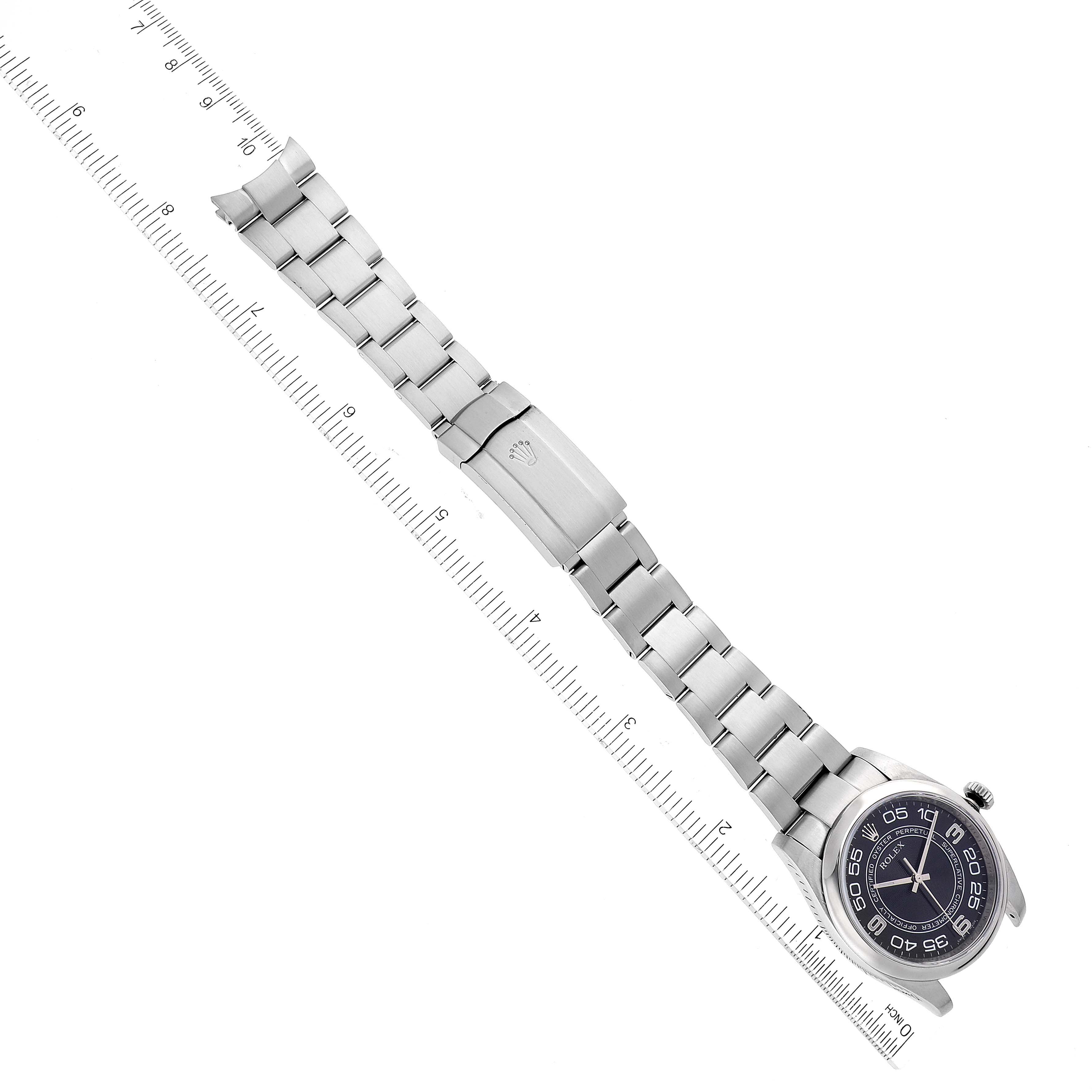 This image shows a top-down view of a Rolex Oyster Perpetual 116000 Men's Stainless Steel Black Dial 116000 Men's Stainless Steel Black Dial watch laid flat next to a ruler.