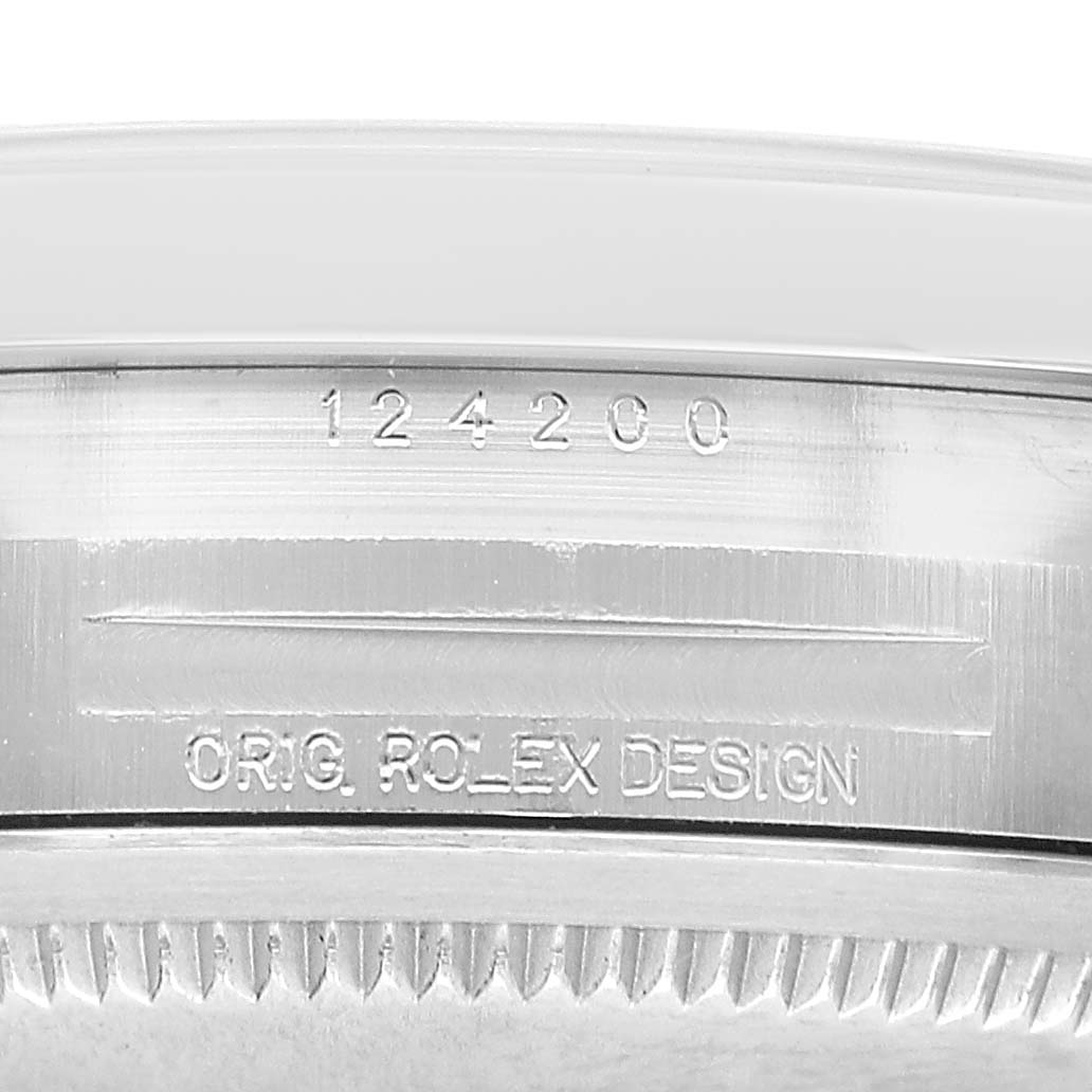 The image shows a close-up of the side casing of a Rolex Oyster Perpetual M124200-0003 Men's Stainless Steel Blue Dial, displaying the model number and "ORIG. ROLEX DESIGN" engraving.