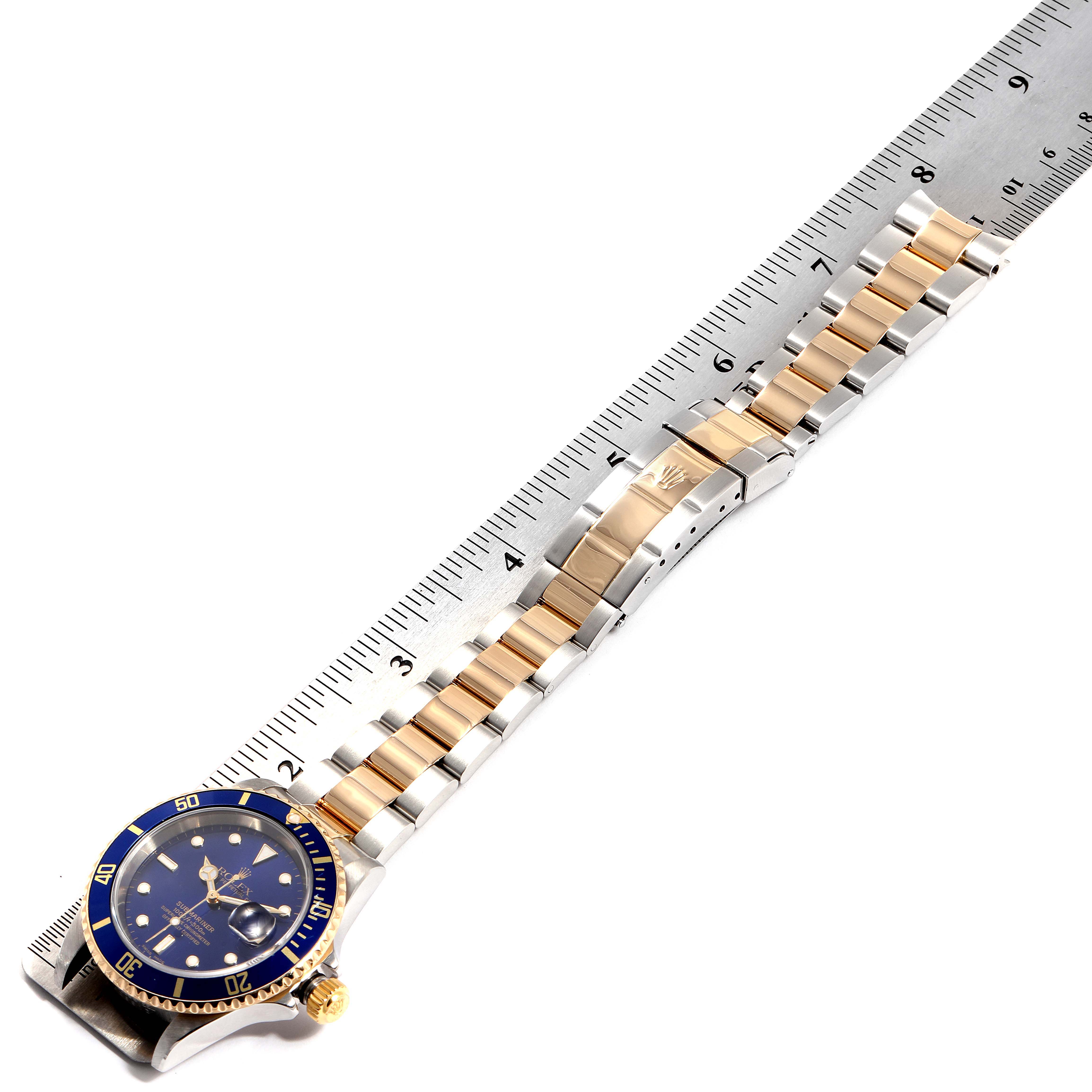 This image shows a Rolex Submariner 16613 Men
s Steel and Gold (two tone) Blue Dial 16613 Men
s Steel and Gold (two tone) Blue Dial watch with a blue dial and gold accents, placed alongside a ruler for measurement.