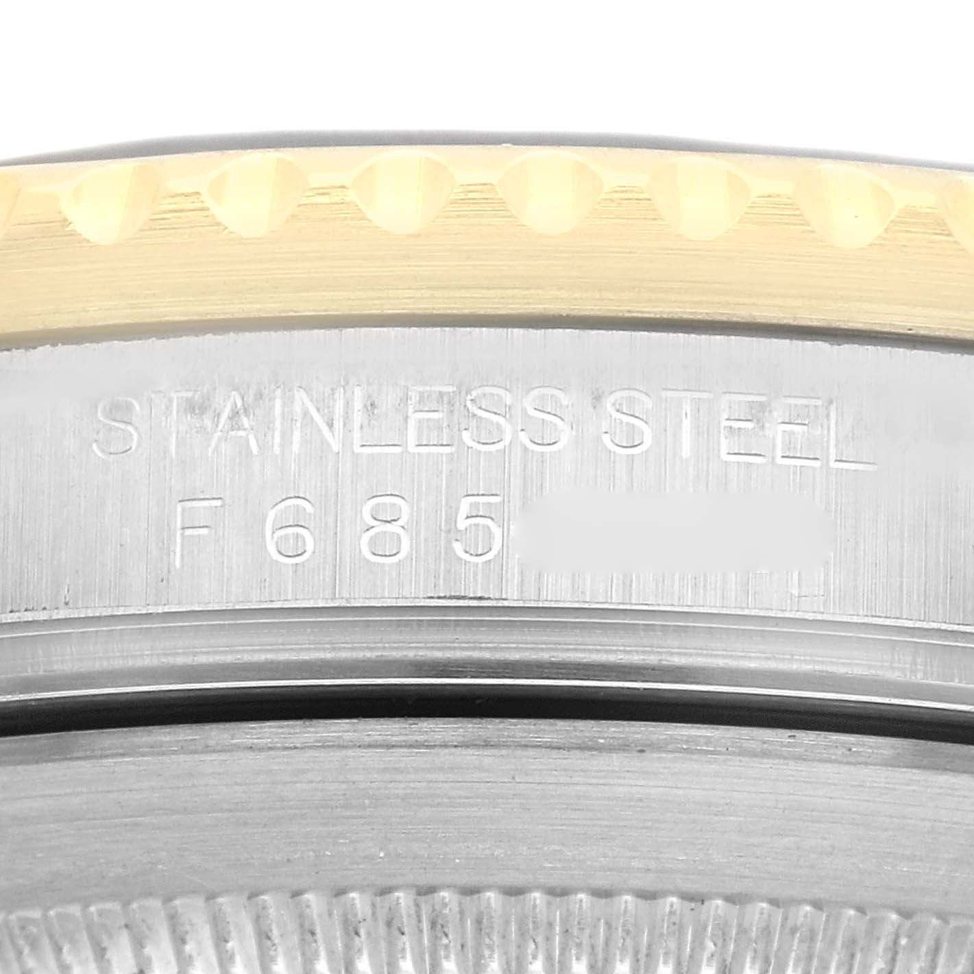 This image shows a macro view of the side of the Rolex Submariner 16613 Men's Steel and Gold (two tone) Black Dial 16613 Men's Steel and Gold (two tone) Black Dial watch case, highlighting the "STAINLESS STEEL" engraving and part of the bezel.