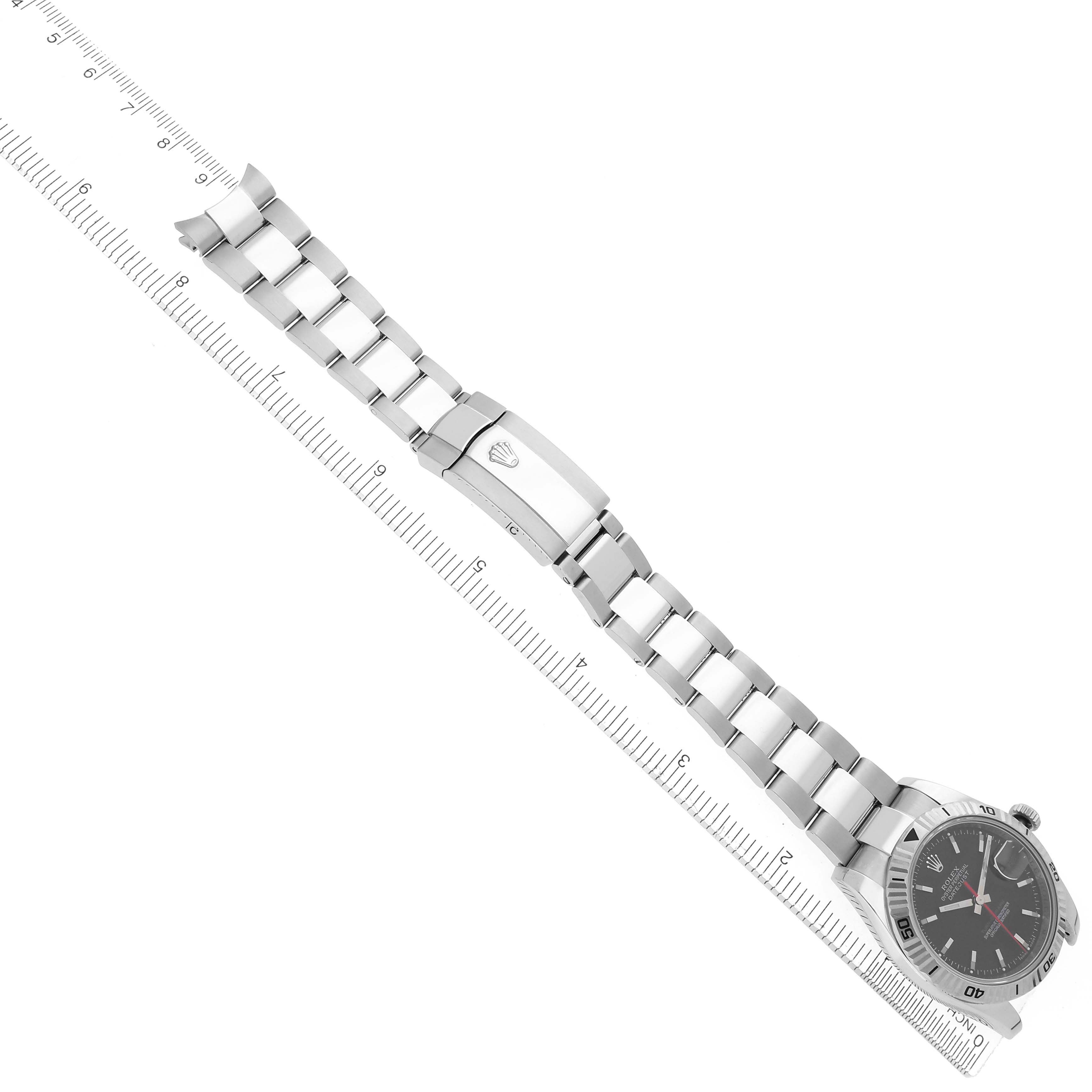 The image shows a Rolex Turn-o-Graph 116264 Men
s Stainless Steel Black Dial 116264 Men
s Stainless Steel Black Dial watch at an angled top view, displaying the face, bezel, bracelet, and clasp alongside a ruler.
