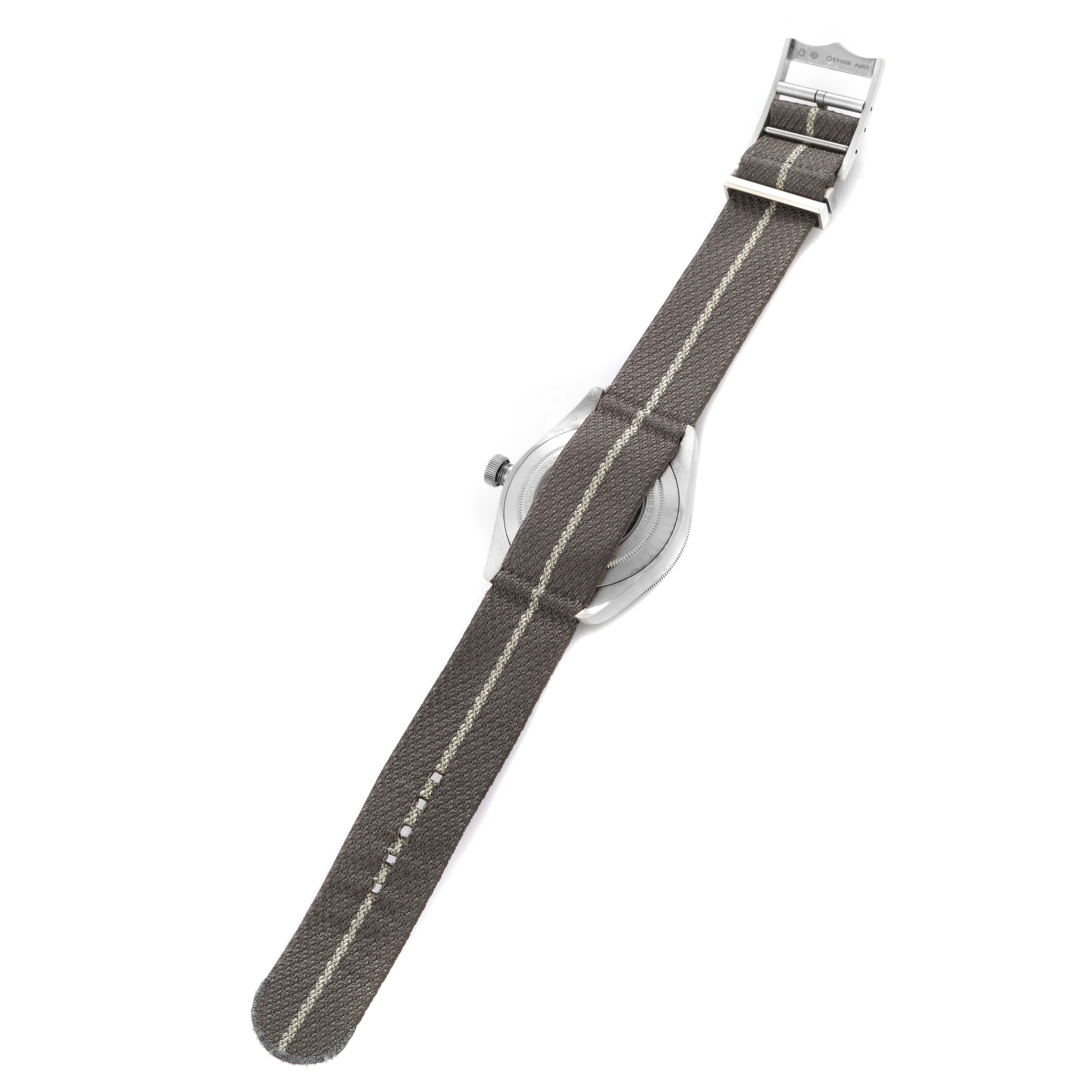 The image shows the Tudor Heritage Black Bay 79010 Men
s Stainless Steel Grey Dial 79010 Men
s Stainless Steel Grey Dial watch from the backside, highlighting its fabric strap and metal clasp.