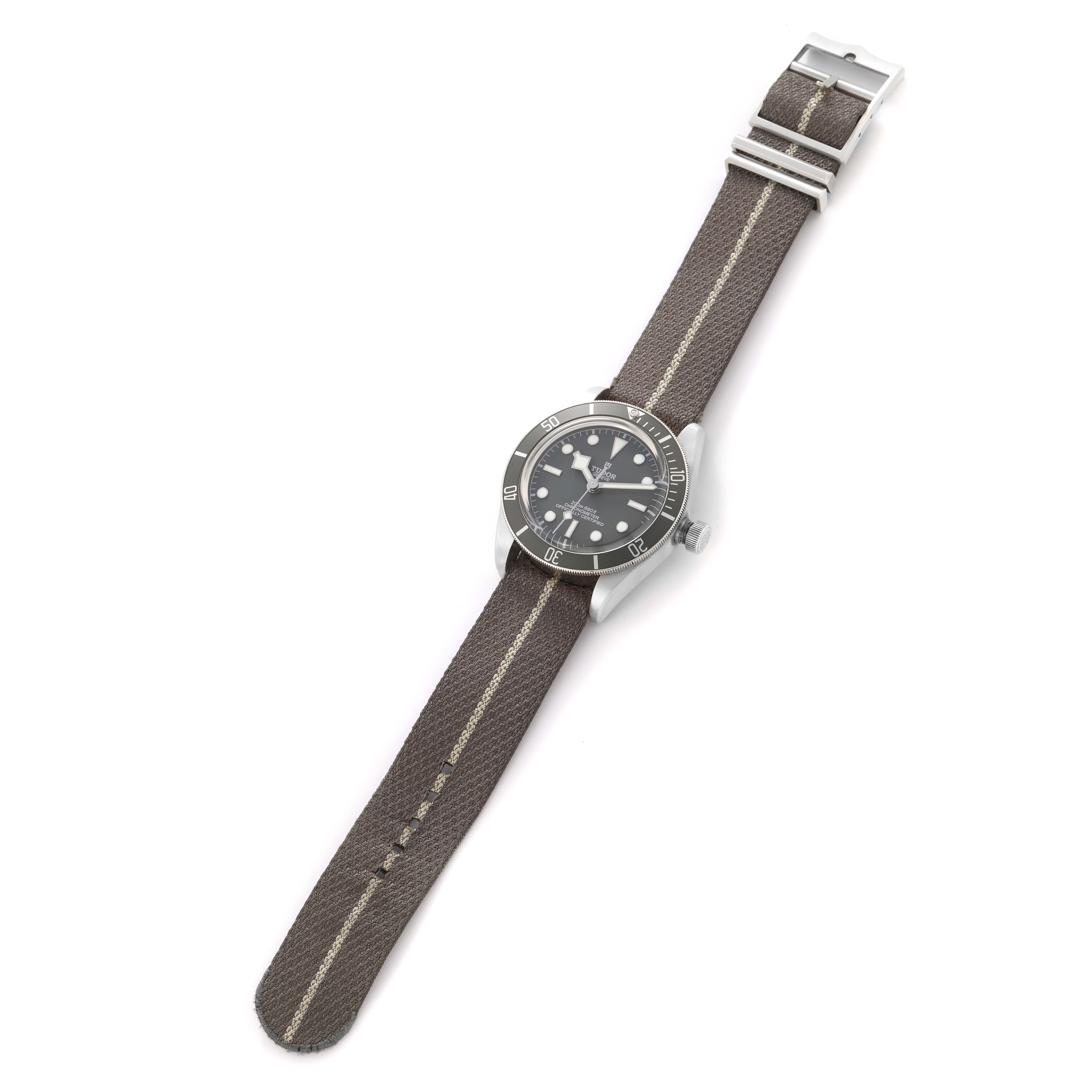 The Tudor Heritage Black Bay 79010 Men
s Stainless Steel Grey Dial 79010 Men
s Stainless Steel Grey Dial watch is shown from a top-down angle, displaying its face, bezel, crown, and fabric strap.