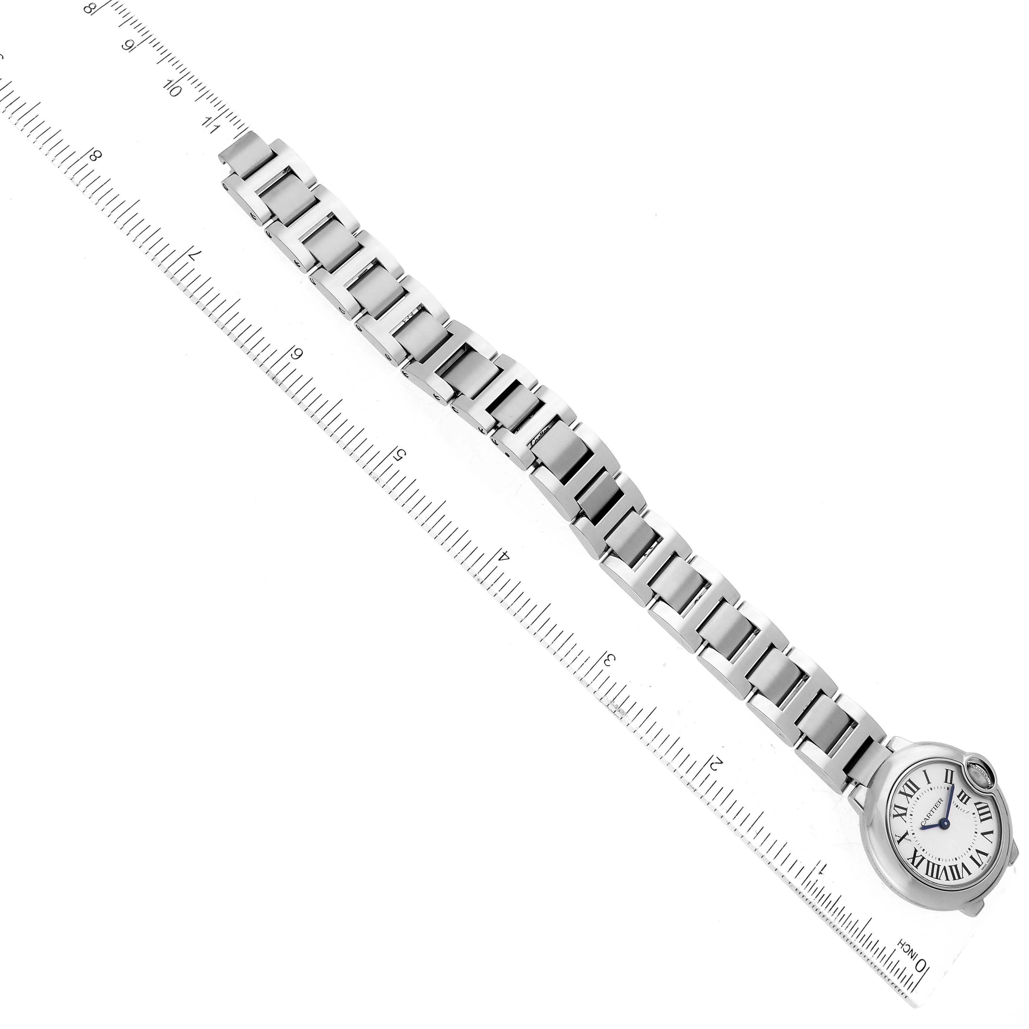The image shows the entire Ballon Bleu watch by Cartier, including its face and metal bracelet, alongside a ruler.