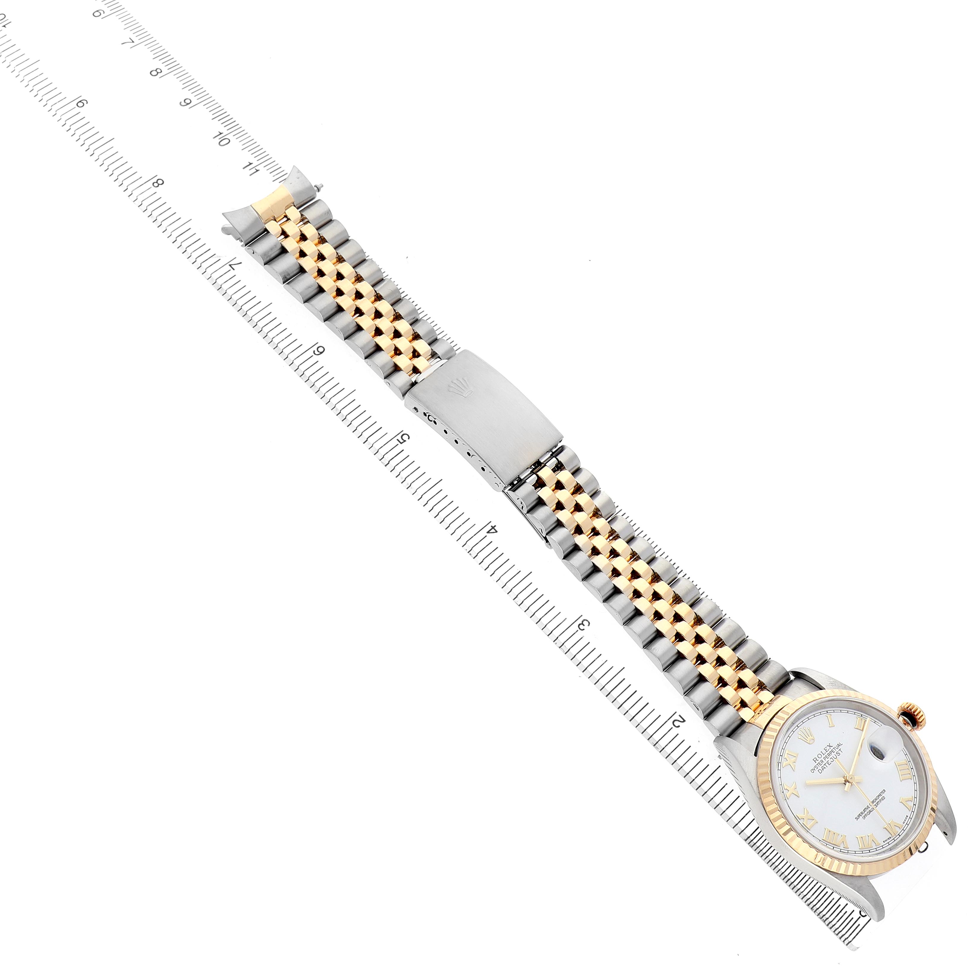 The Rolex Datejust 16233 Men's Steel and Gold (two tone) White Dial watch is displayed laid flat from an overhead angle, showing the band and face alongside a ruler for scale.