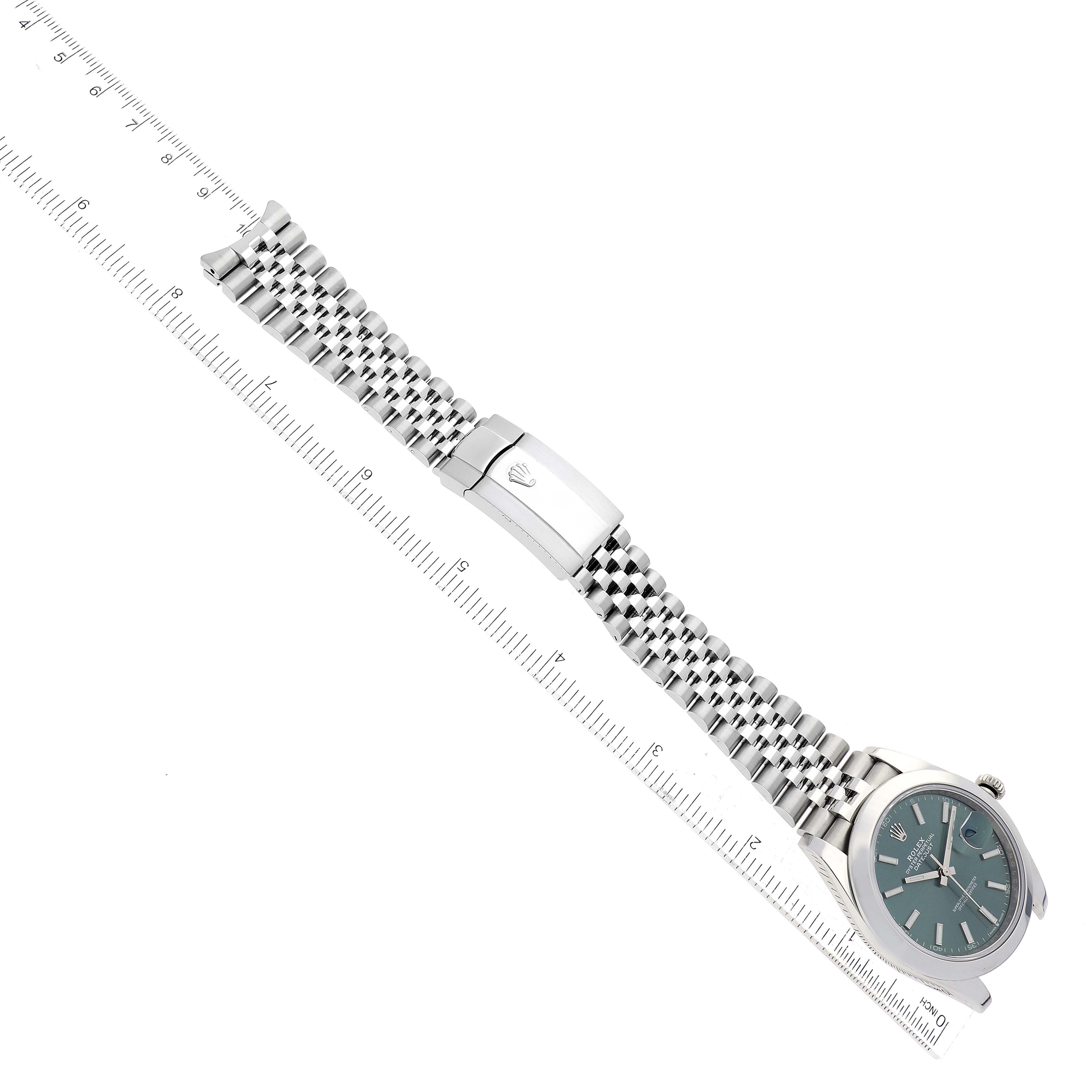 The Rolex Datejust 41 126300 Men's Stainless Steel Green Dial 126300 Men's Stainless Steel Green Dial watch is displayed from an angled top view showing the face, bezel, bracelet, and clasp alongside a ruler.