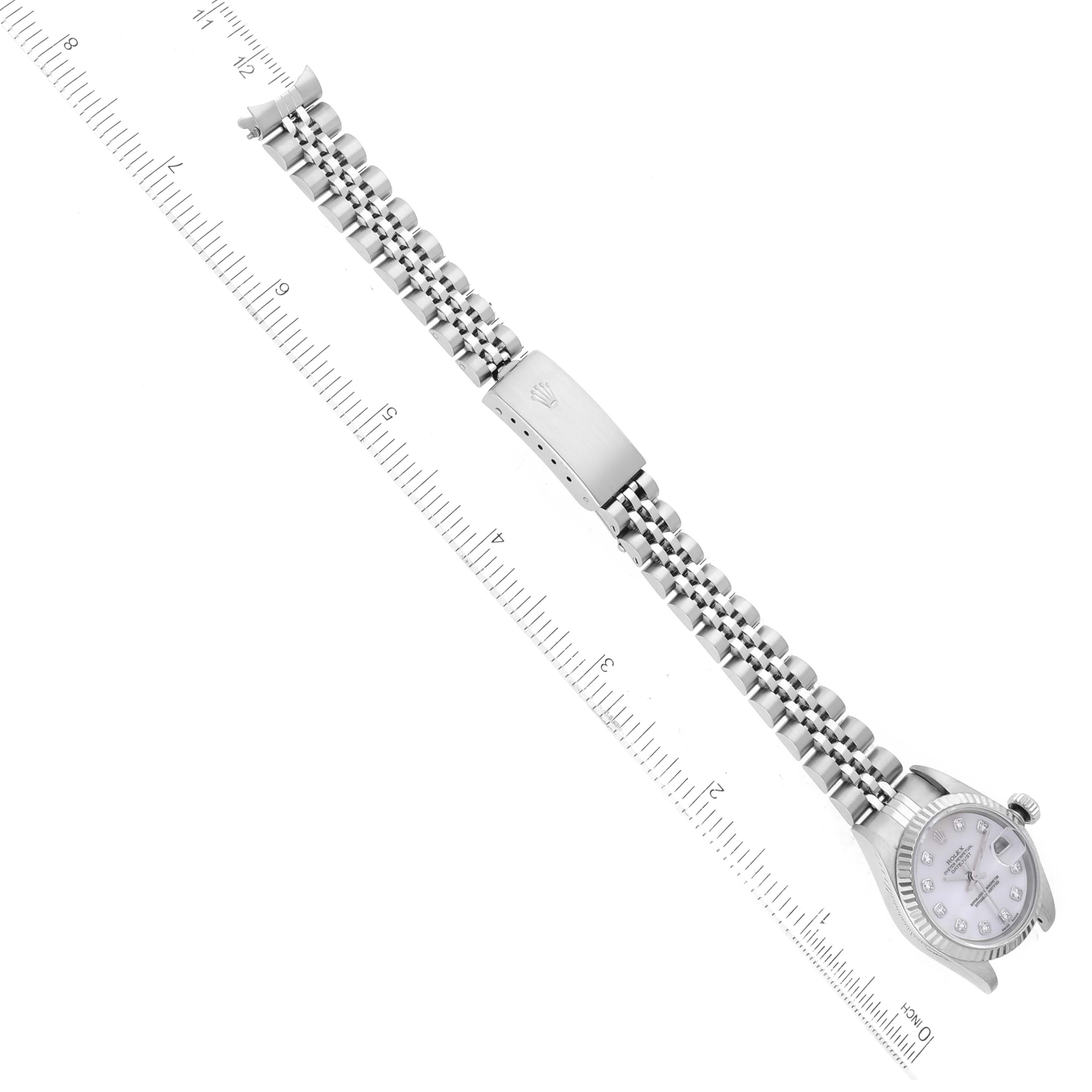 This image shows a top-down view of a Rolex Datejust 79174 Women's Stainless Steel Mother of Pearl Dial 79174 Women's Stainless Steel Mother of Pearl Dial watch and its linked bracelet alongside a ruler for scale.