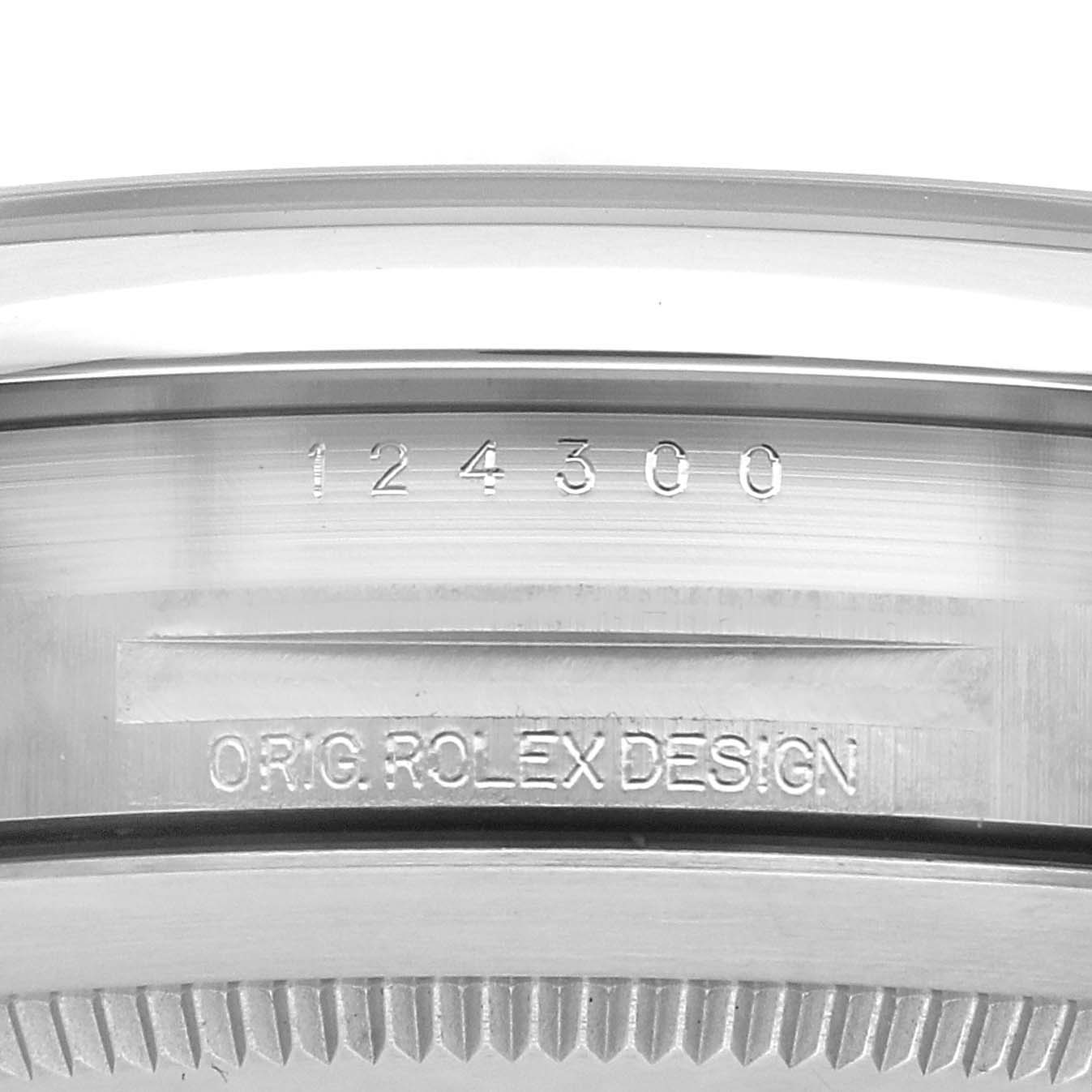 The image shows the side of a Rolex Oyster Perpetual 124300 Men
s Stainless Steel Green Dial 124300 Men
s Stainless Steel Green Dial watch case, highlighting the model number and "ORIG. ROLEX DESIGN" engraving.