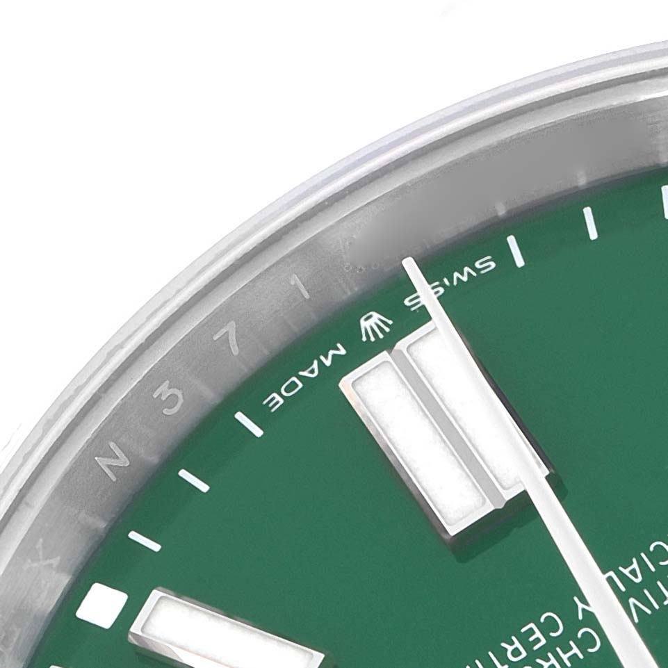 The image shows a close-up of the dial of the Rolex Oyster Perpetual 124300 Men
s Stainless Steel Green Dial 124300 Men
s Stainless Steel Green Dial watch, focusing on the hour markers and text.