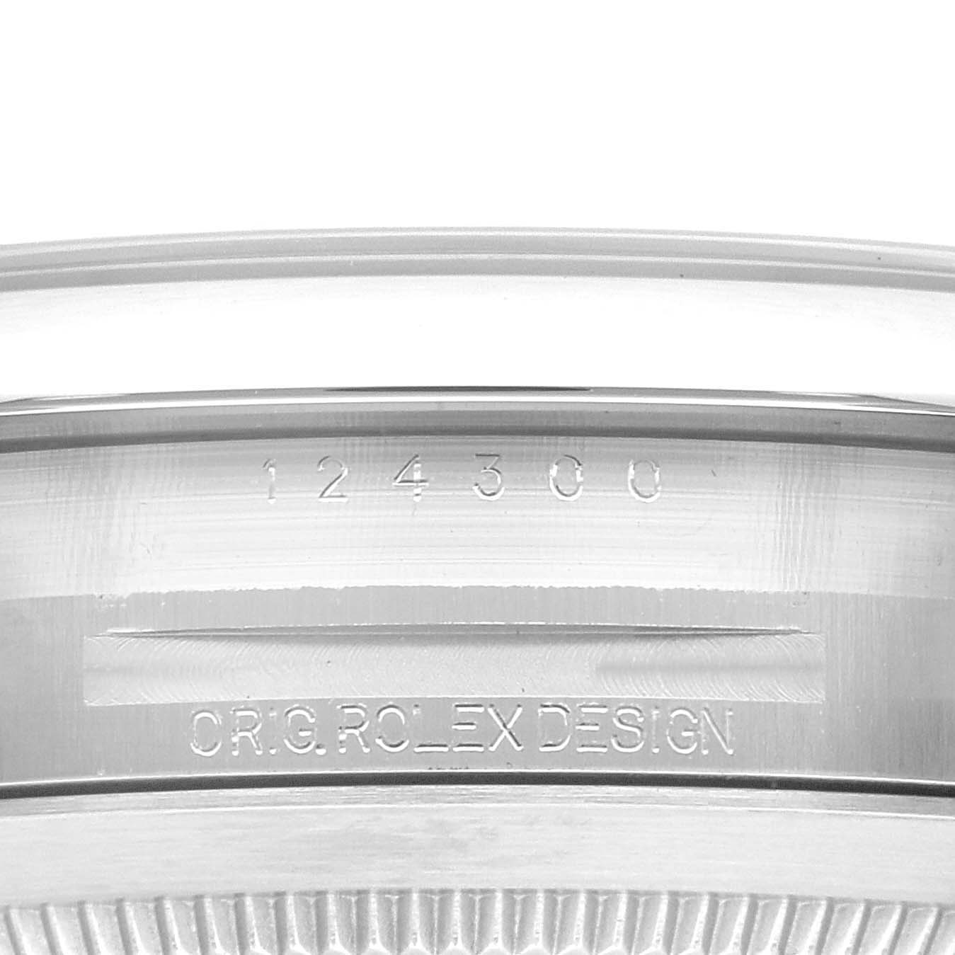 The image shows a close-up of the case side of a Rolex Oyster Perpetual 124300 Men
s Stainless Steel Yellow Dial 124300 Men
s Stainless Steel Yellow Dial watch, displaying its serial number and "ORIG. ROLEX DESIGN" engraving.