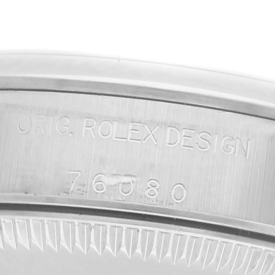 The image shows a close-up of the side of a Rolex Oyster Perpetual 76080 Women
s Stainless Steel Blue Dial 76080 Women
s Stainless Steel Blue Dial watch, highlighting the engraved design and model number.